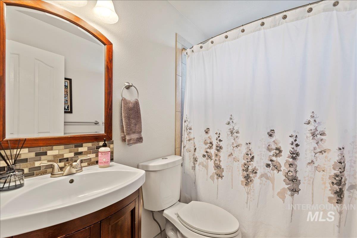 Bathroom featuring a shower with curtain, backsplash, and vanity