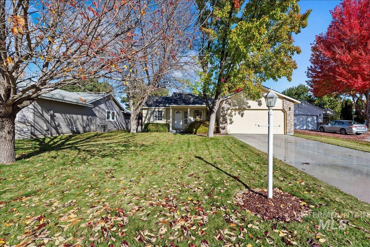 View of front facade featuring a front yard, driveway, and an attached garage