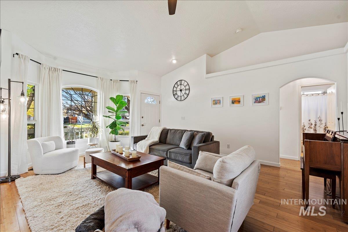 Living room featuring light wood-style floors, vaulted ceiling, arched walkways, and recessed lighting