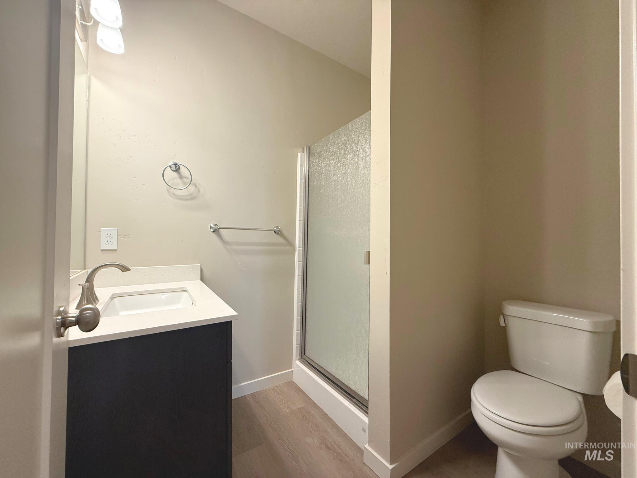 Bathroom featuring vanity, a stall shower, and dark wood-type flooring