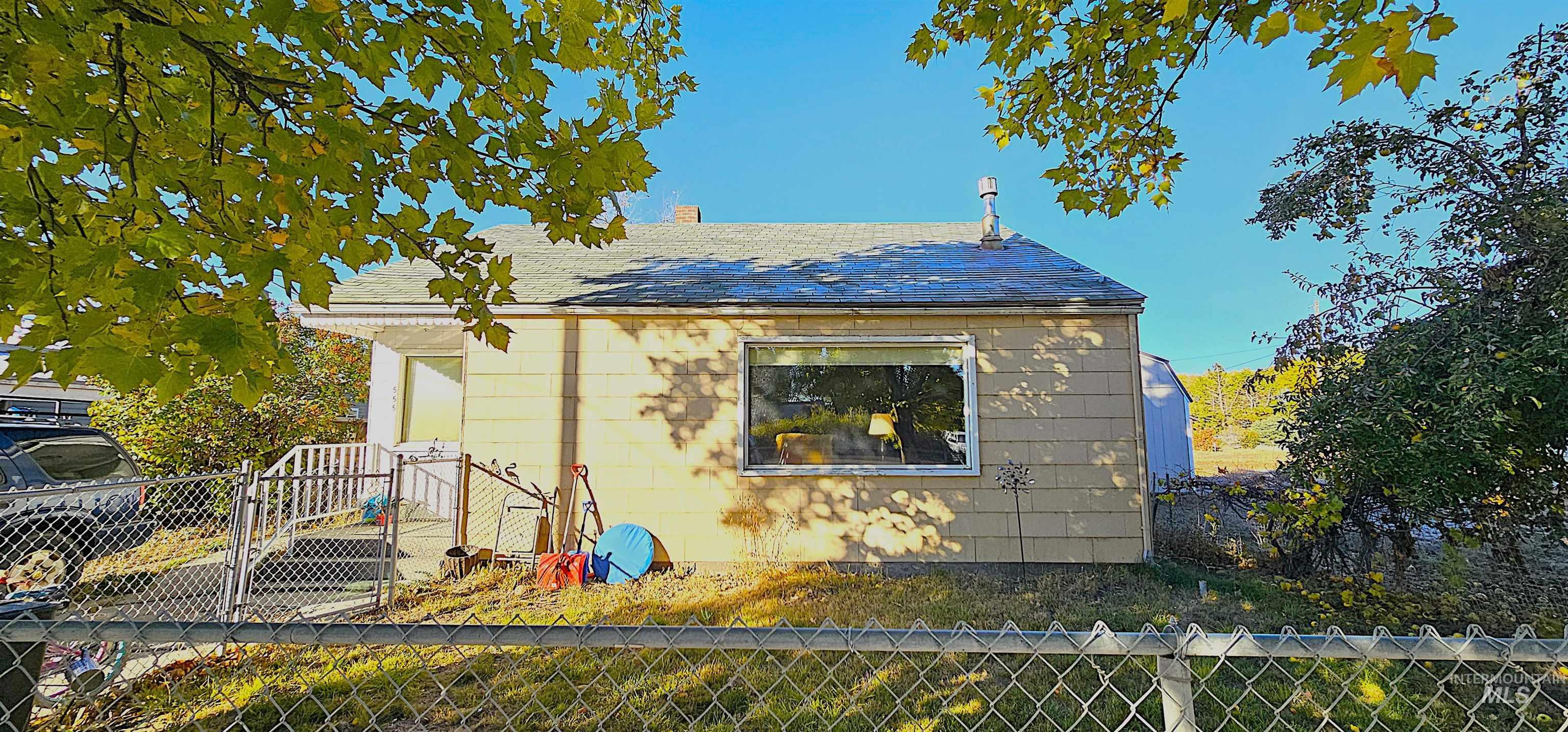 View of side of home featuring a fenced backyard, a chimney, and a shingled roof