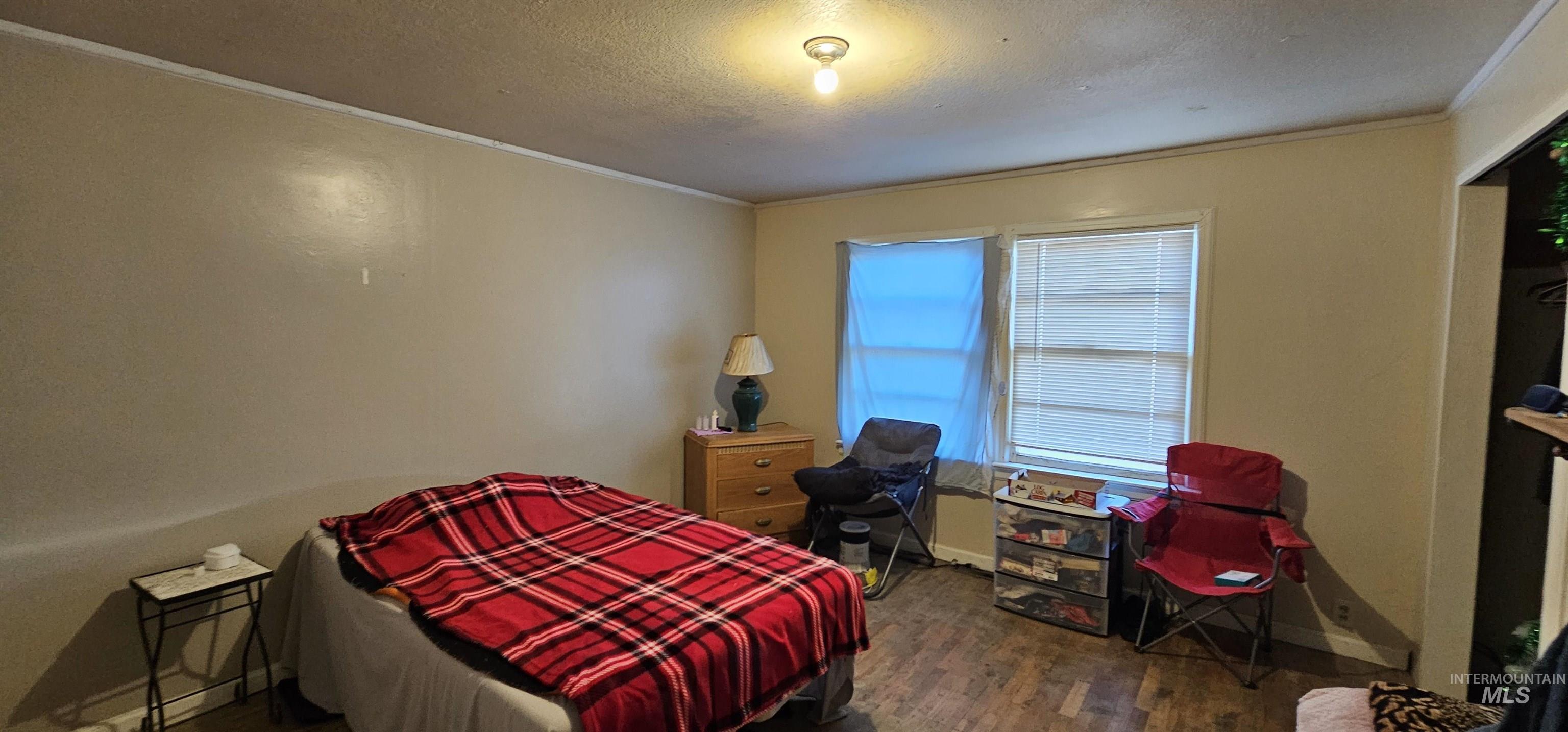Bedroom with dark wood-style floors, crown molding, and a textured ceiling