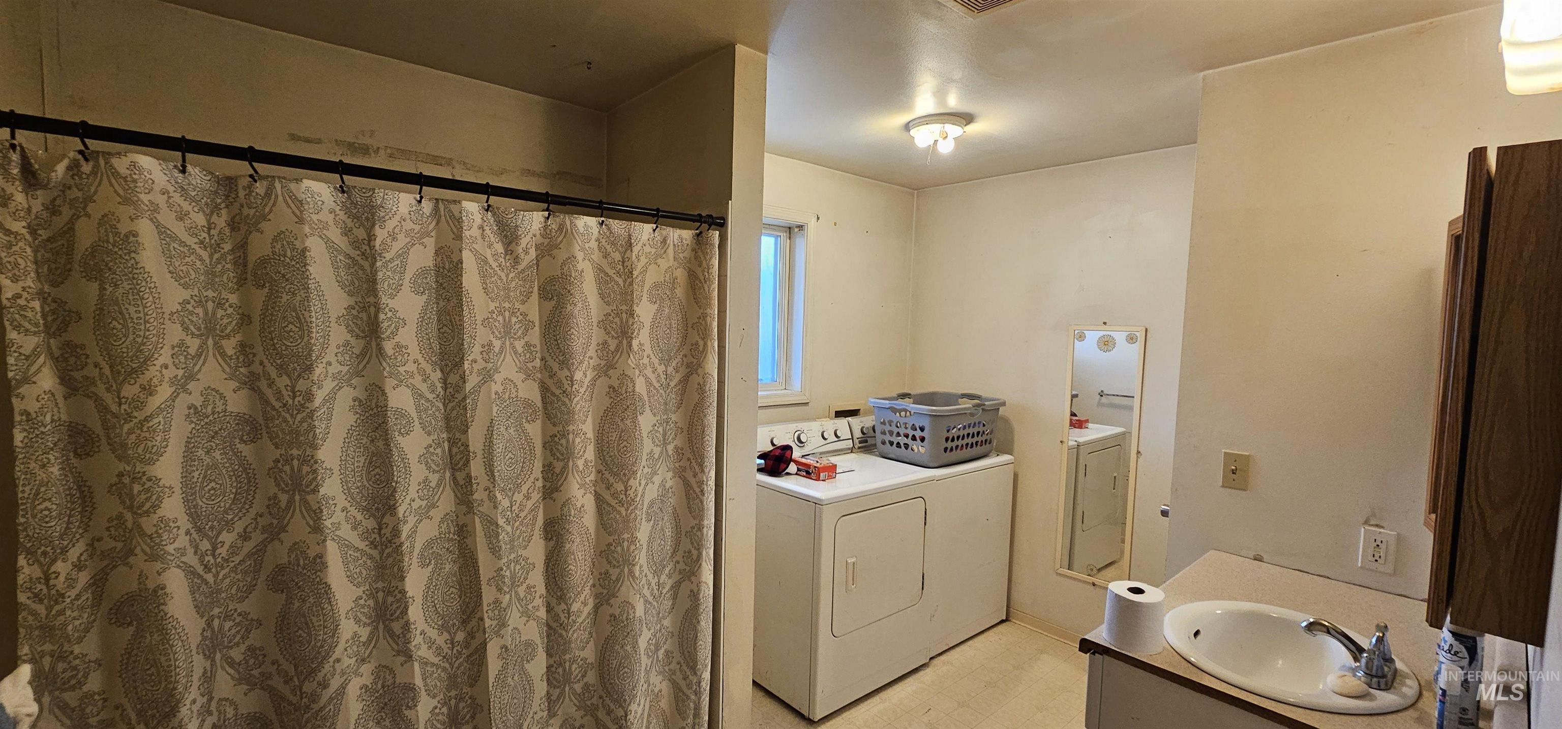 Full bathroom featuring vanity, separate washer and dryer, and curtained shower