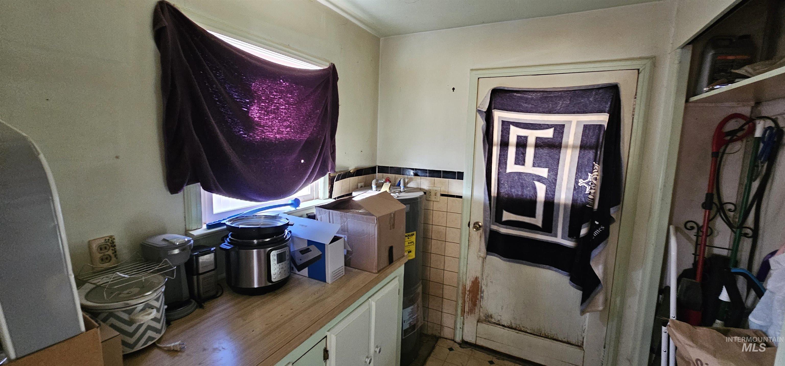 Interior space featuring tile walls and electric water heater