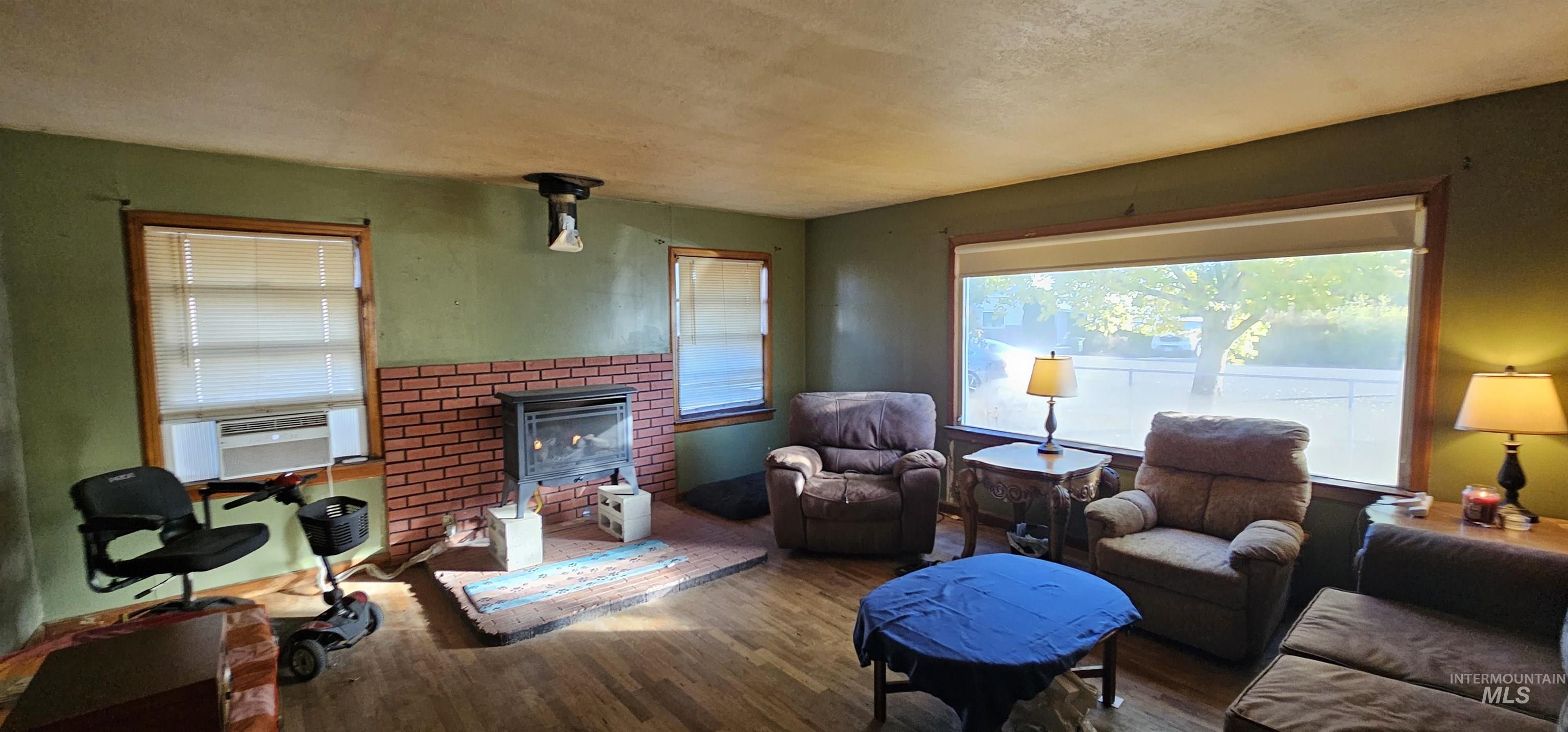Living area featuring wood finished floors, a fireplace, a textured ceiling, and cooling unit