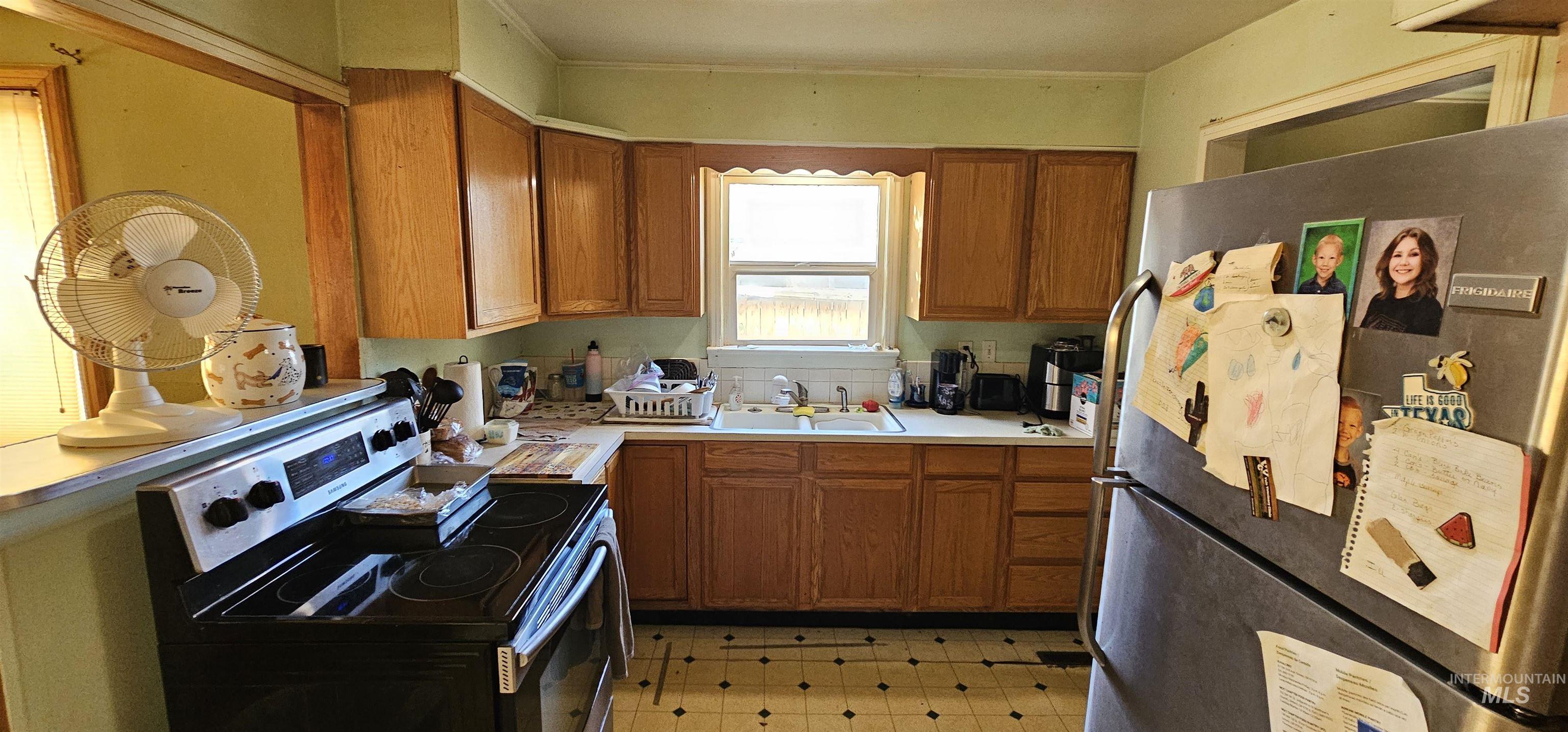 Kitchen featuring stainless steel appliances, light countertops, brown cabinets, and light flooring