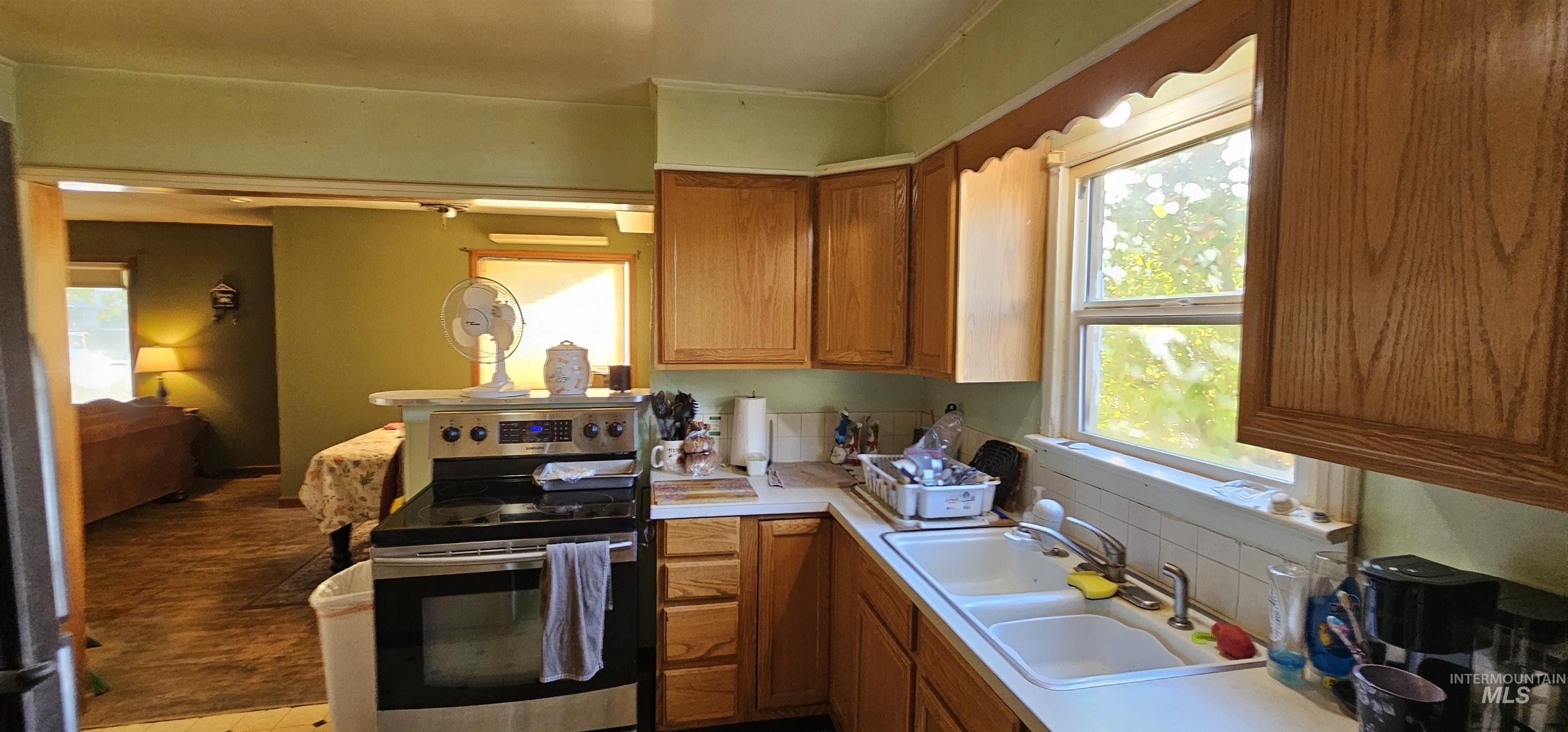 Kitchen featuring electric range, light countertops, brown cabinets, and plenty of natural light