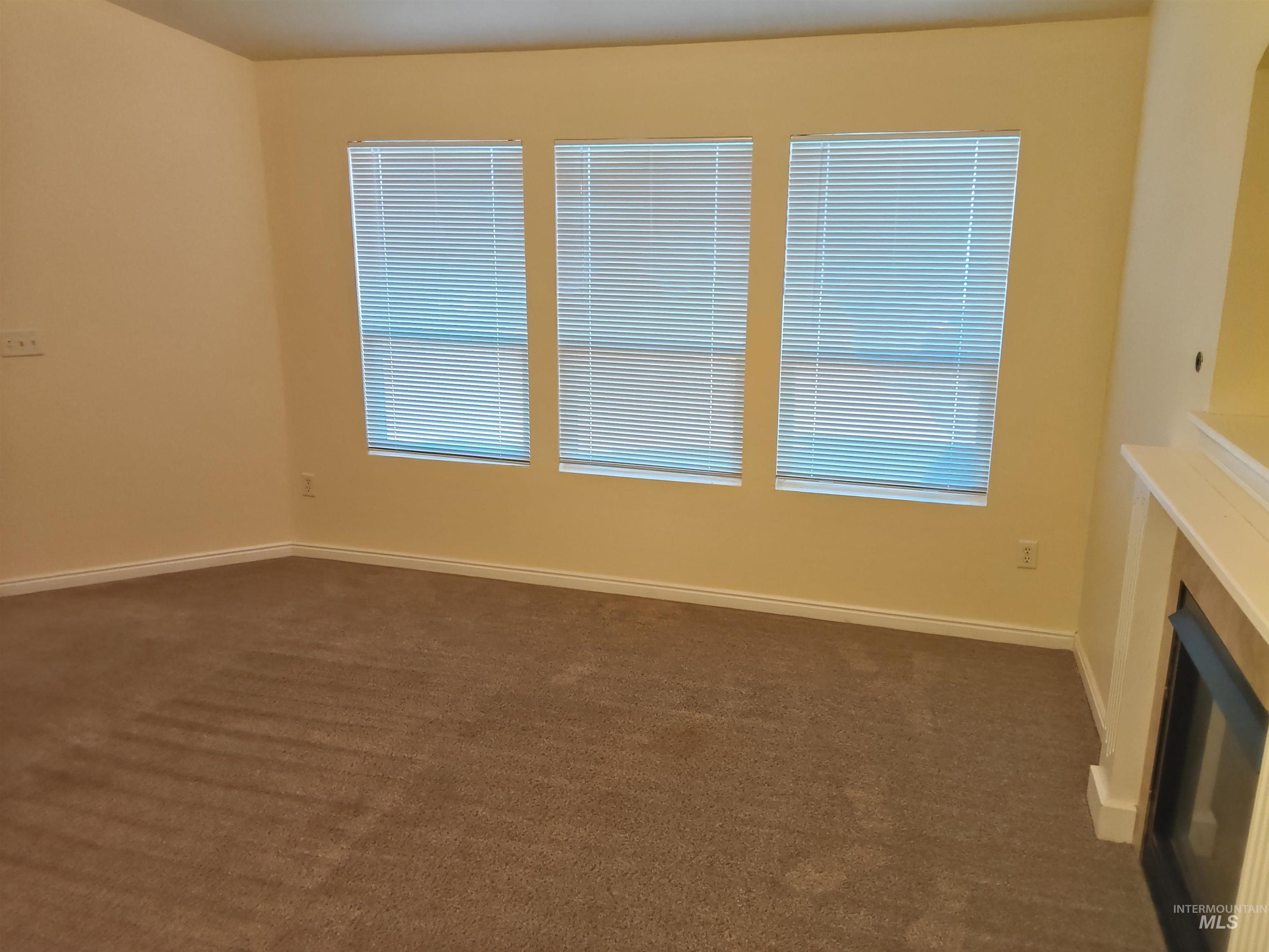 Empty room with dark carpet and baseboards