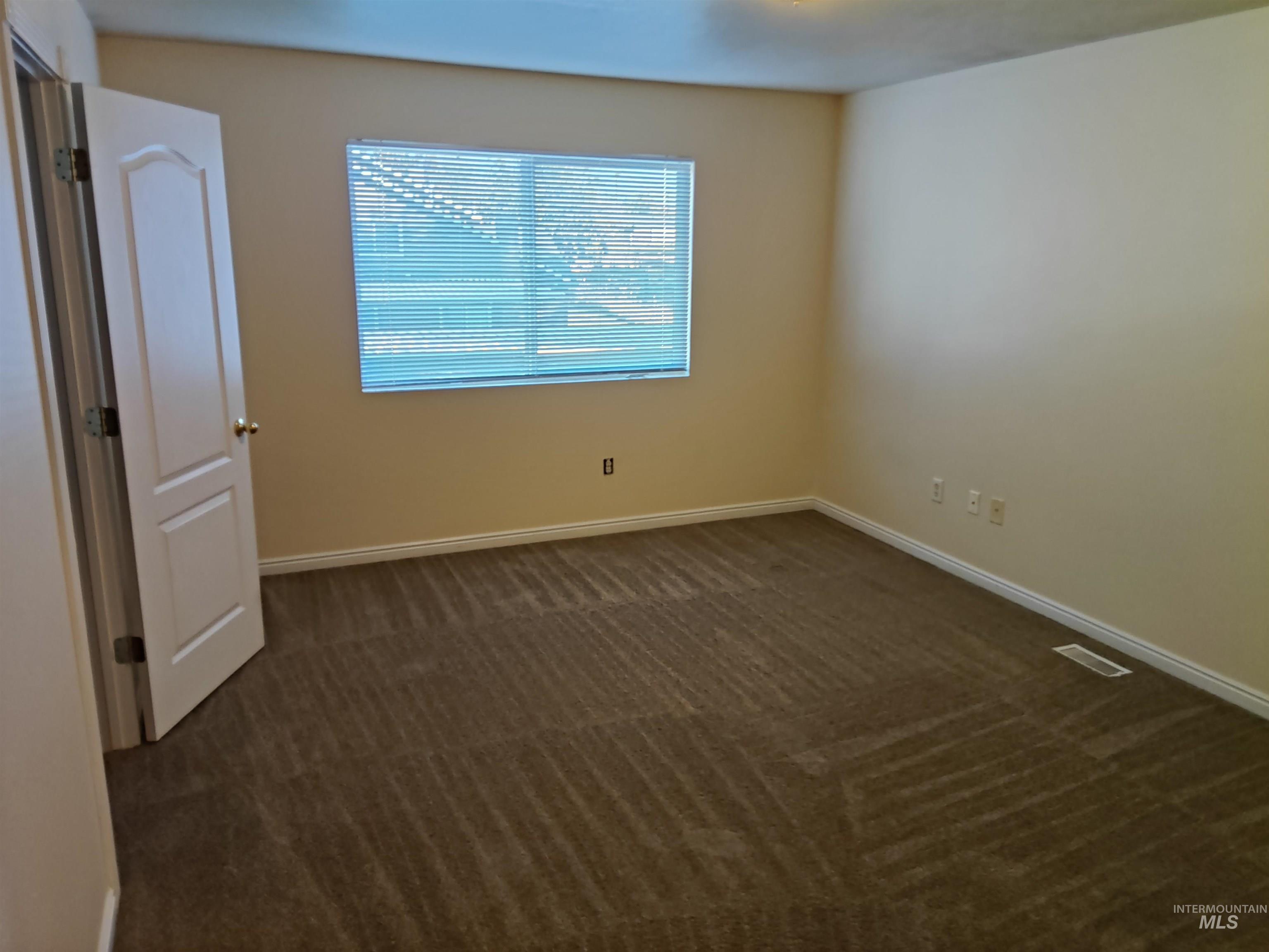 Spare room with dark colored carpet and baseboards