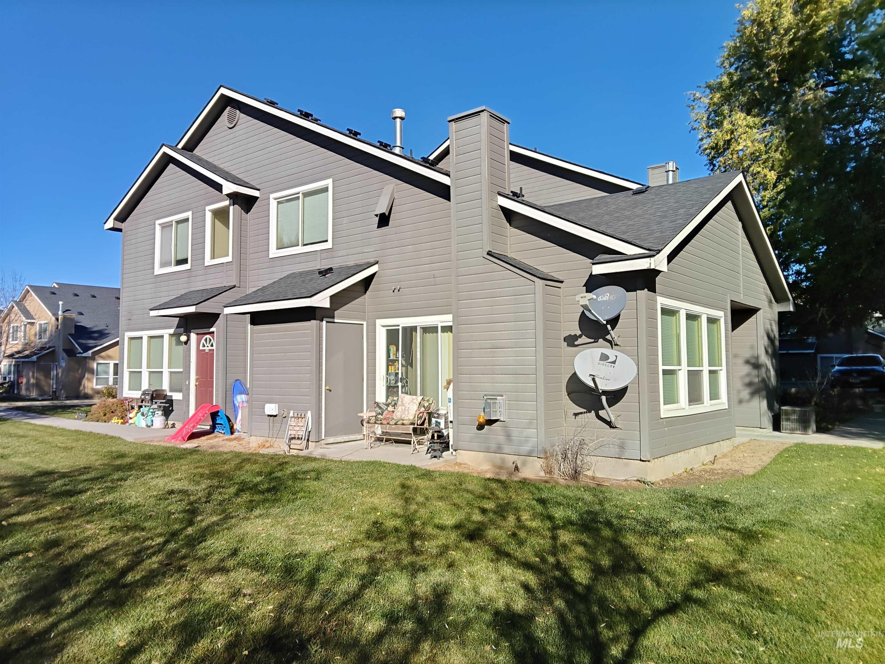 Rear view of property with a chimney, a lawn, and roof with shingles