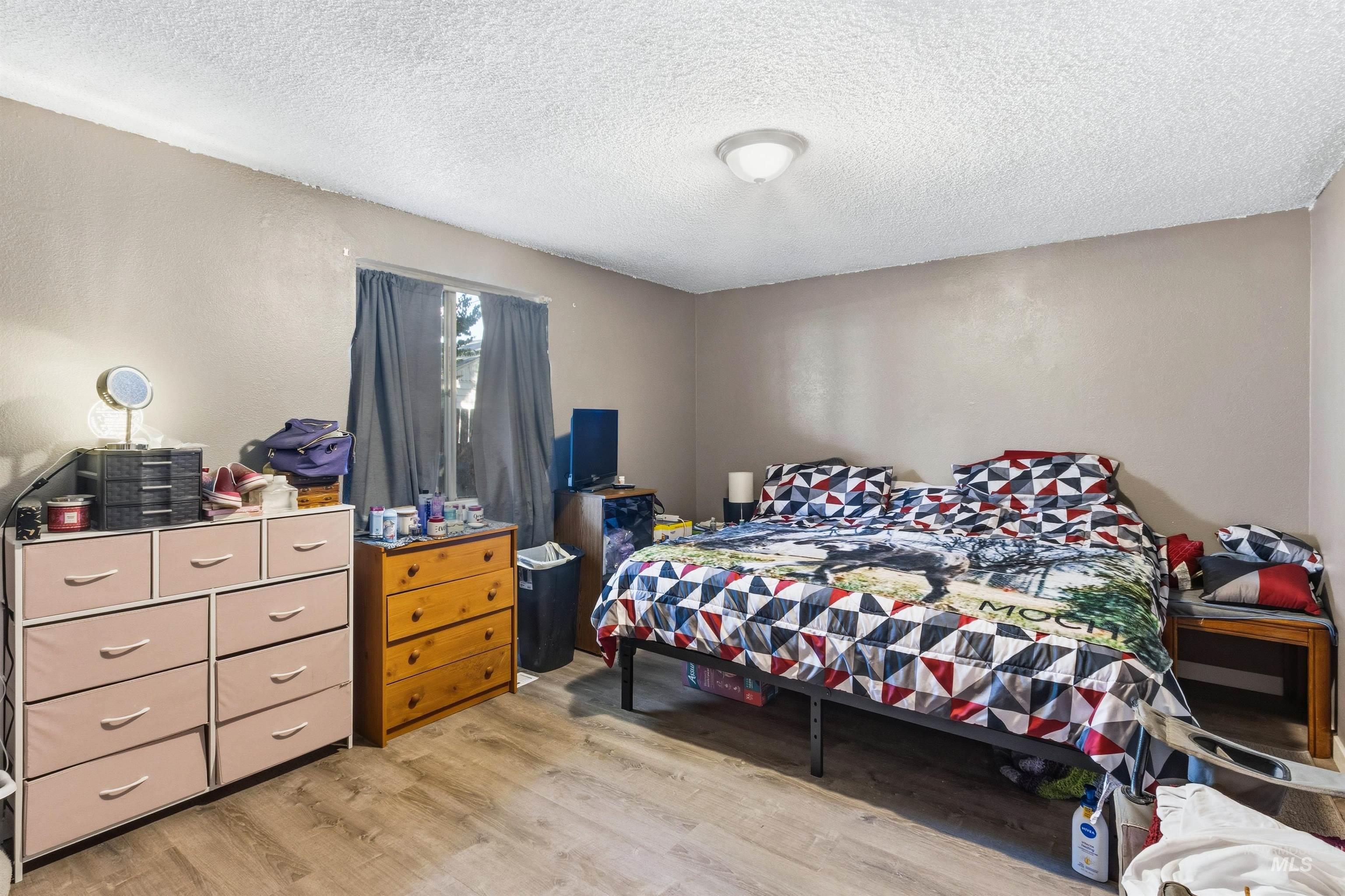 Bedroom with a textured ceiling and light wood finished floors
