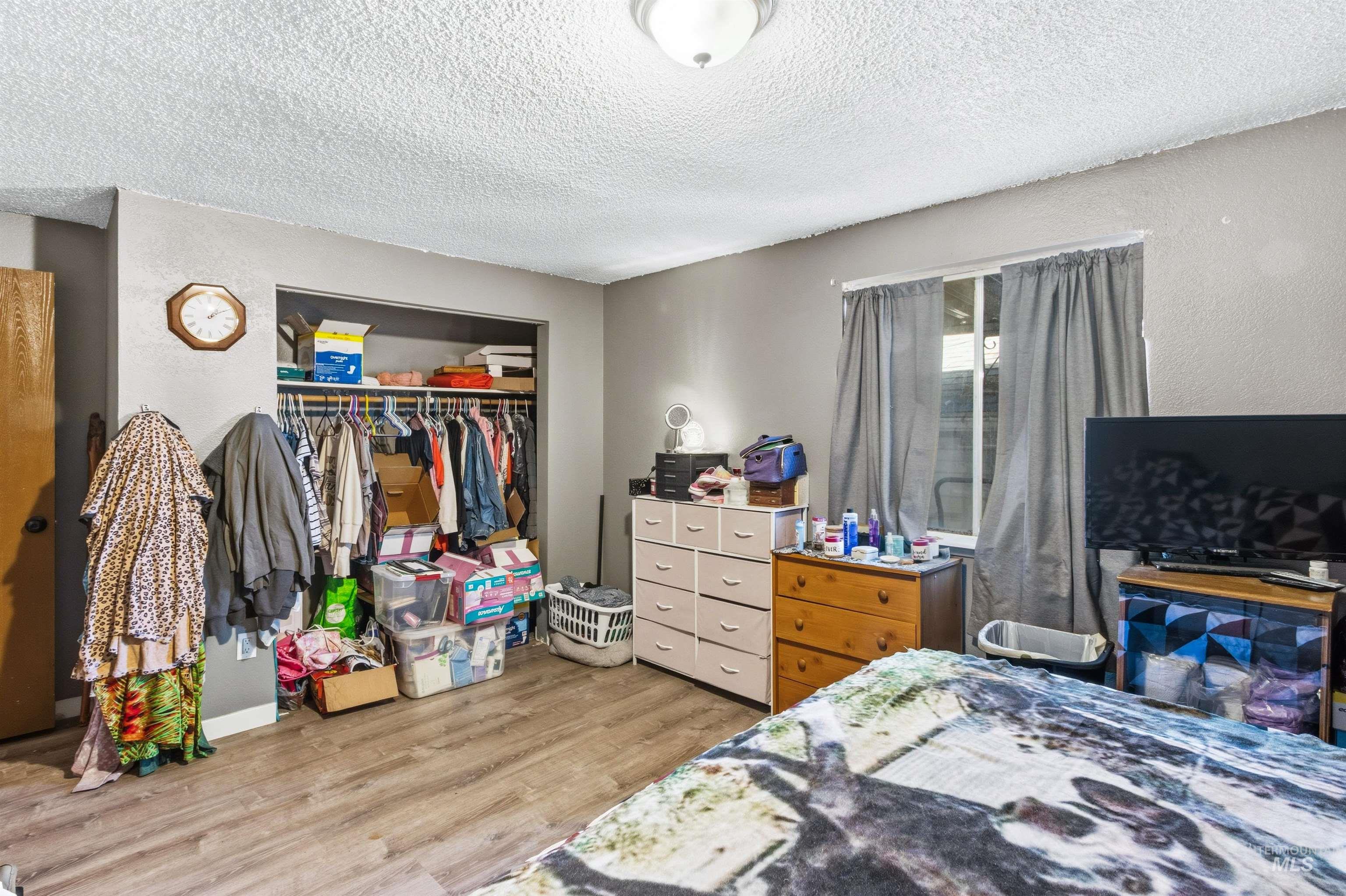 Bedroom with a textured ceiling, light wood-style floors, a closet, and a textured wall