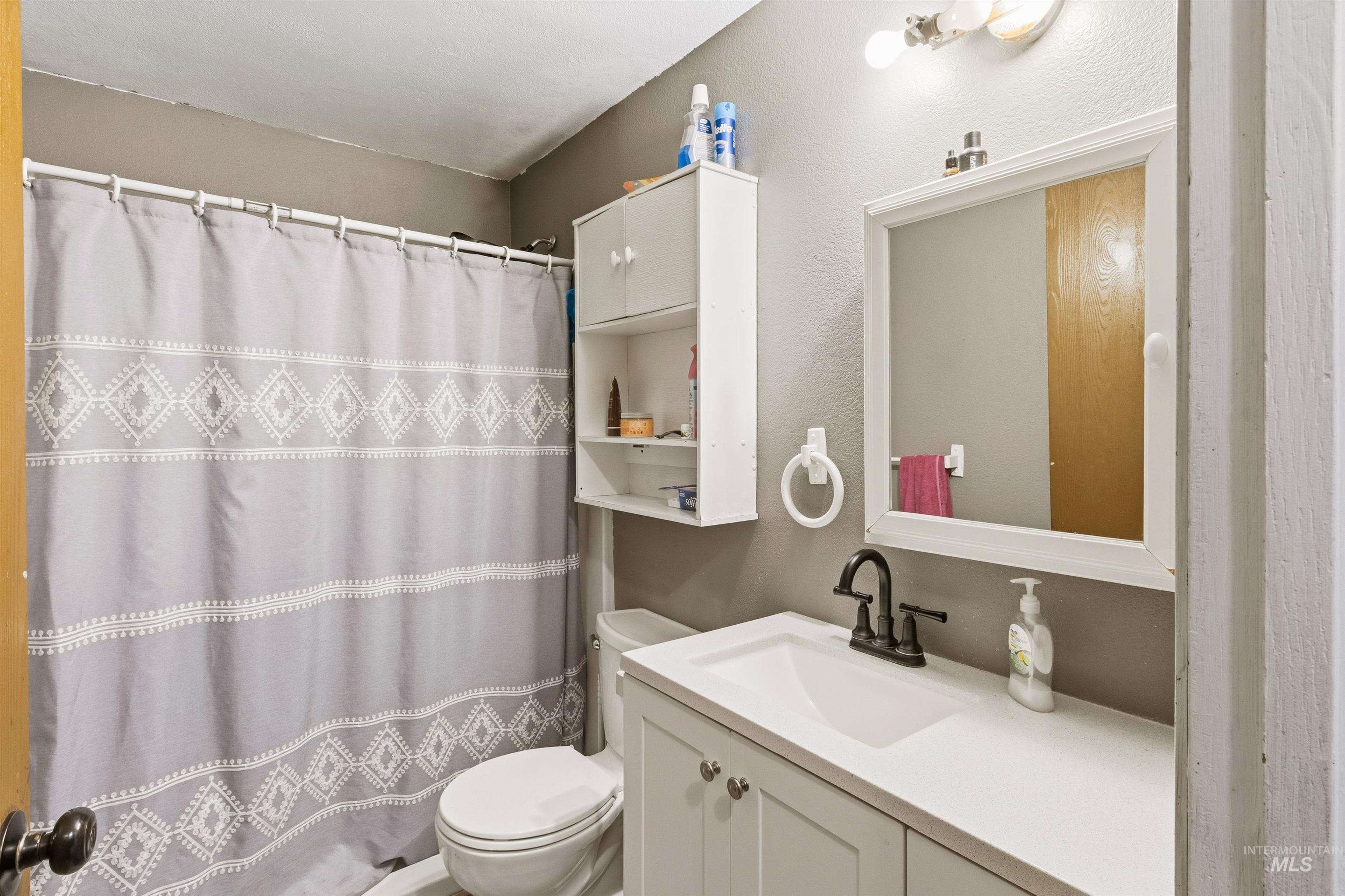 Full bath with a shower with curtain, vanity, and a textured wall