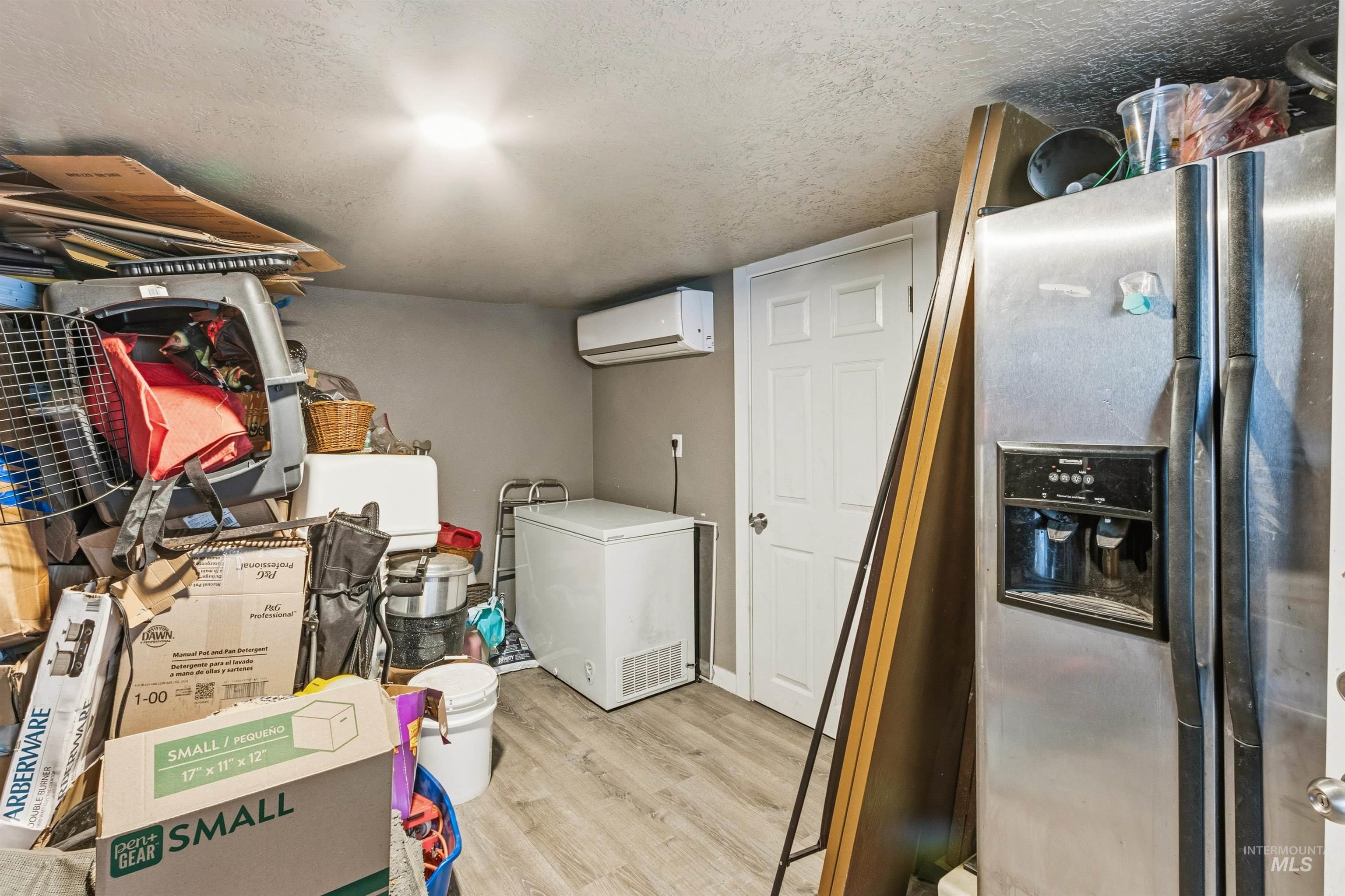 Laundry area featuring light wood-style floors, a textured ceiling, and an AC wall unit