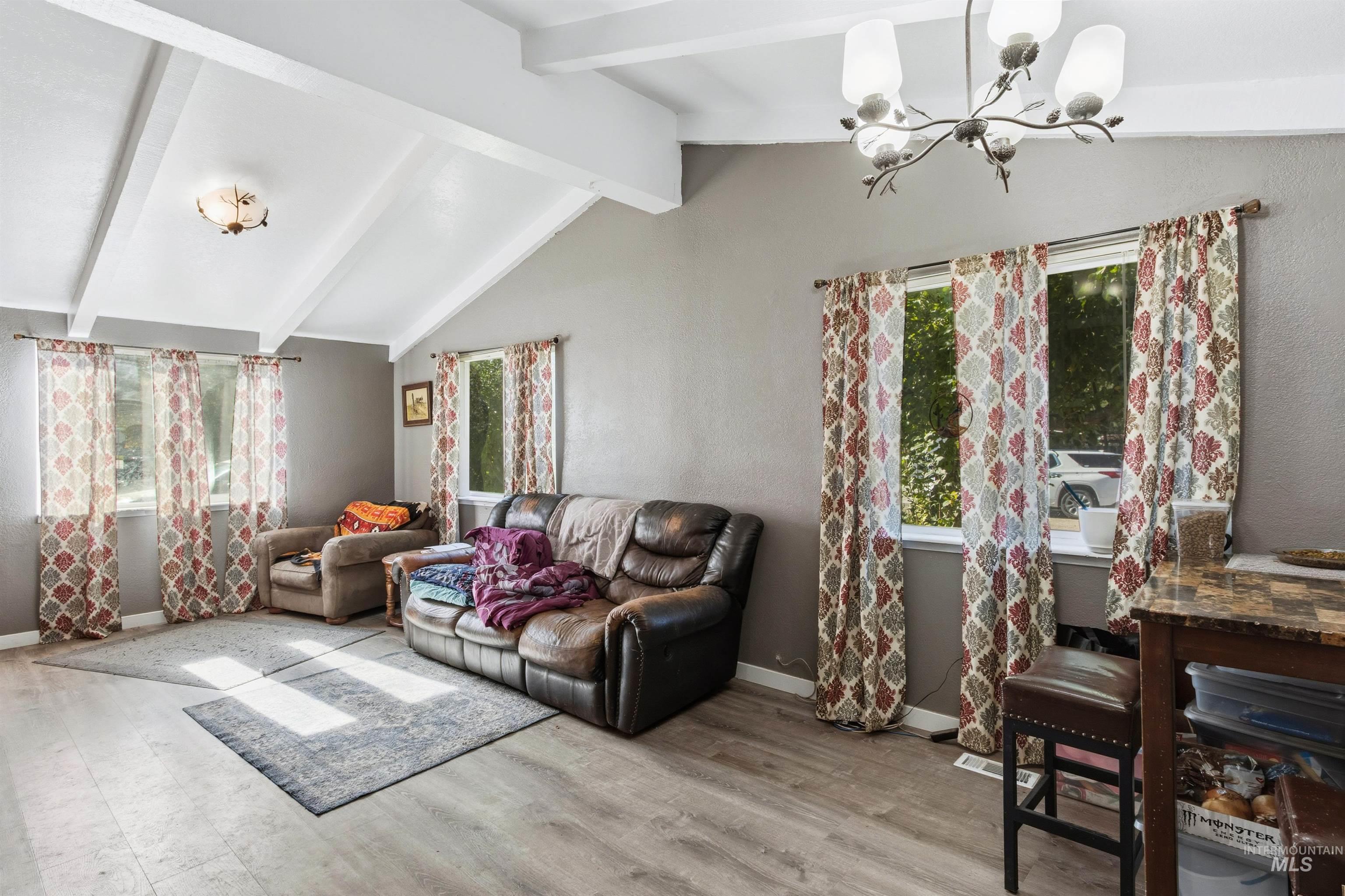 Living room with healthy amount of natural light, light wood finished floors, and a chandelier
