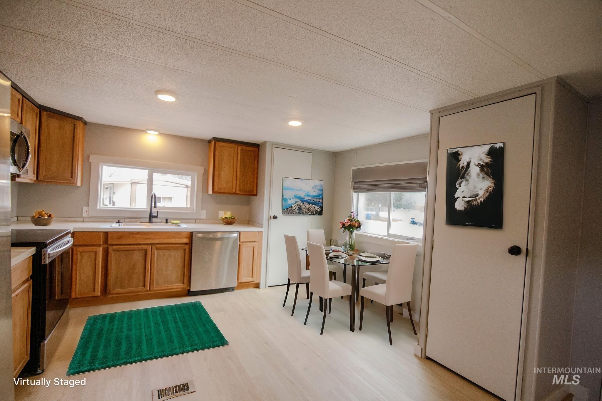 Kitchen featuring light countertops, stainless steel appliances, brown cabinets, light wood-style flooring, and recessed lighting