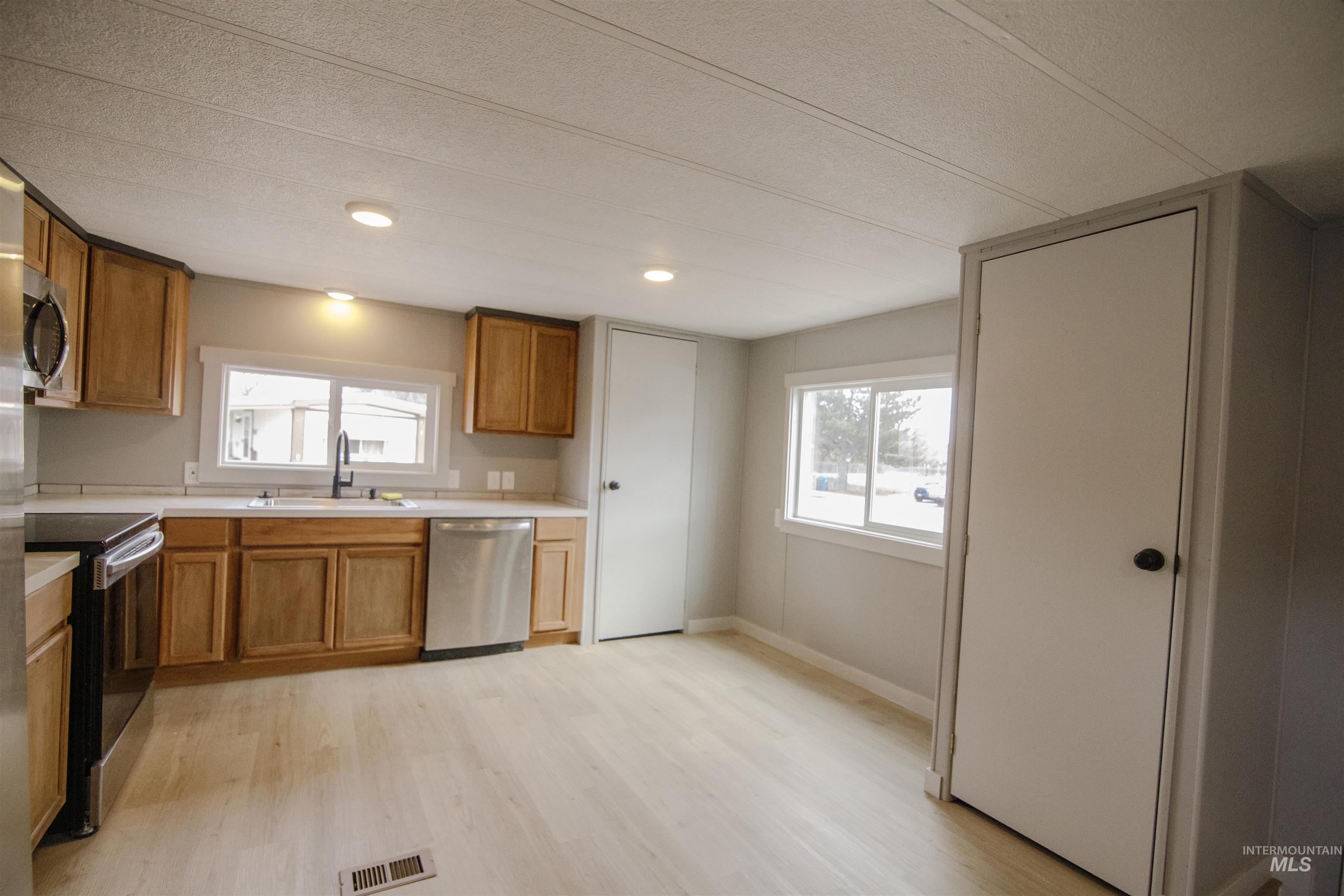 Kitchen with light countertops, brown cabinets, appliances with stainless steel finishes, light wood finished floors, and recessed lighting