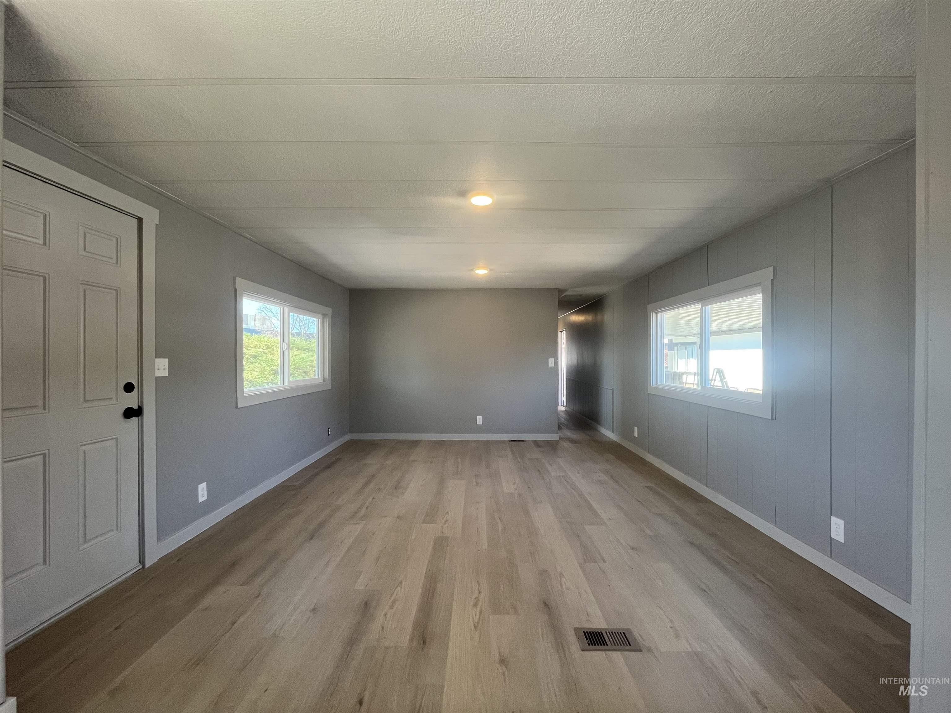 Unfurnished living room featuring light wood-style floors, healthy amount of natural light, and a textured ceiling