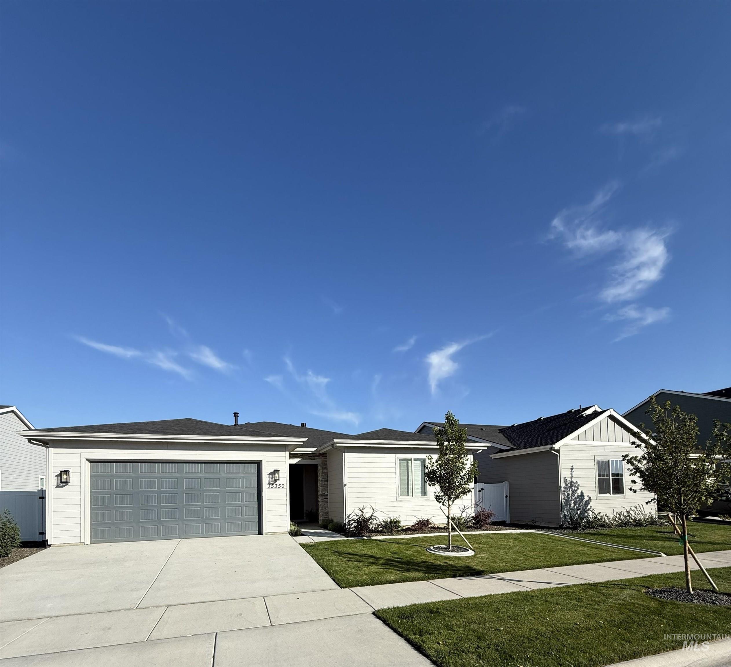 Single story home featuring a front lawn, a garage, concrete driveway, and board and batten siding