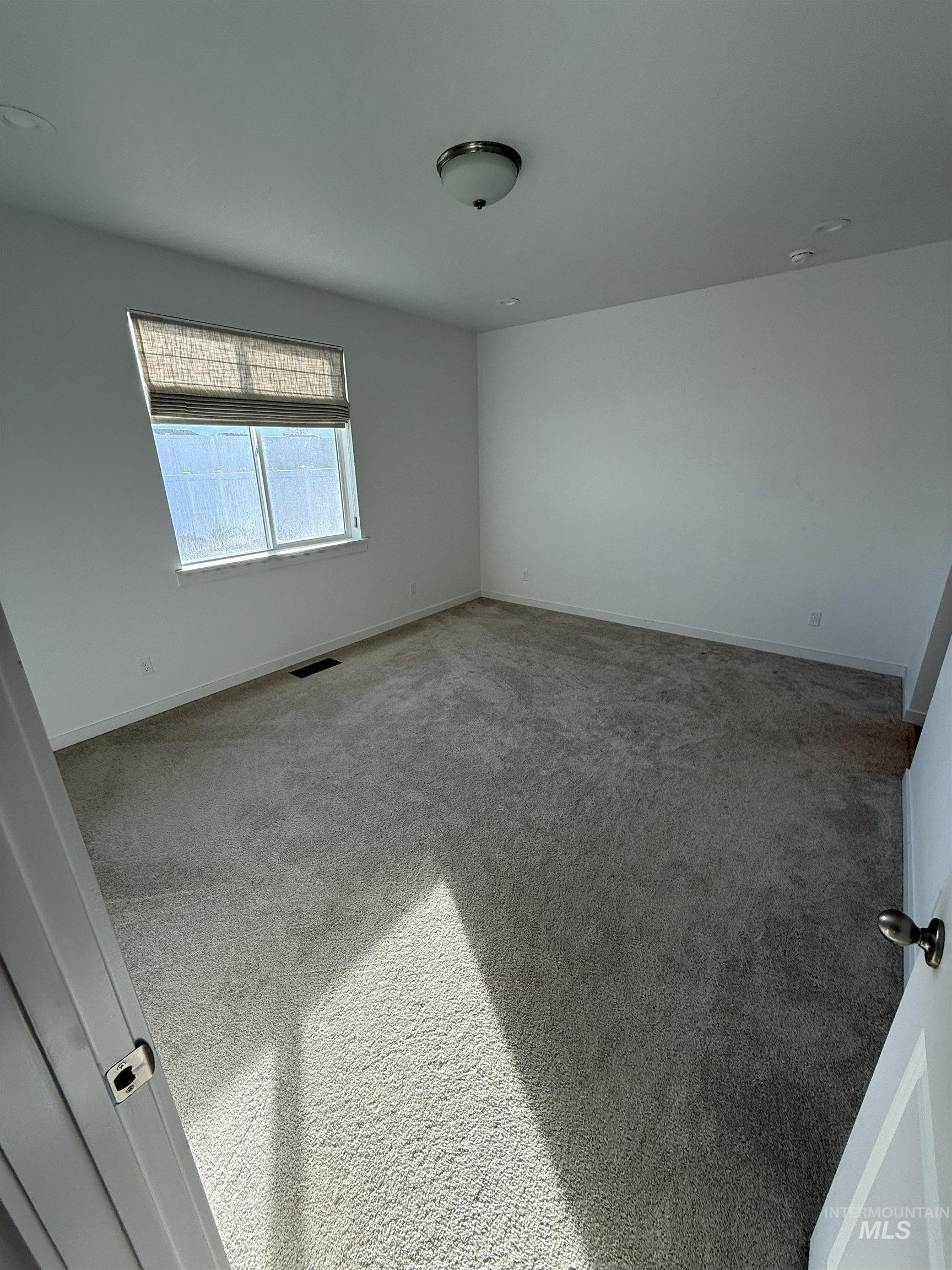 large primary bedroom with carpet and custom window coverings