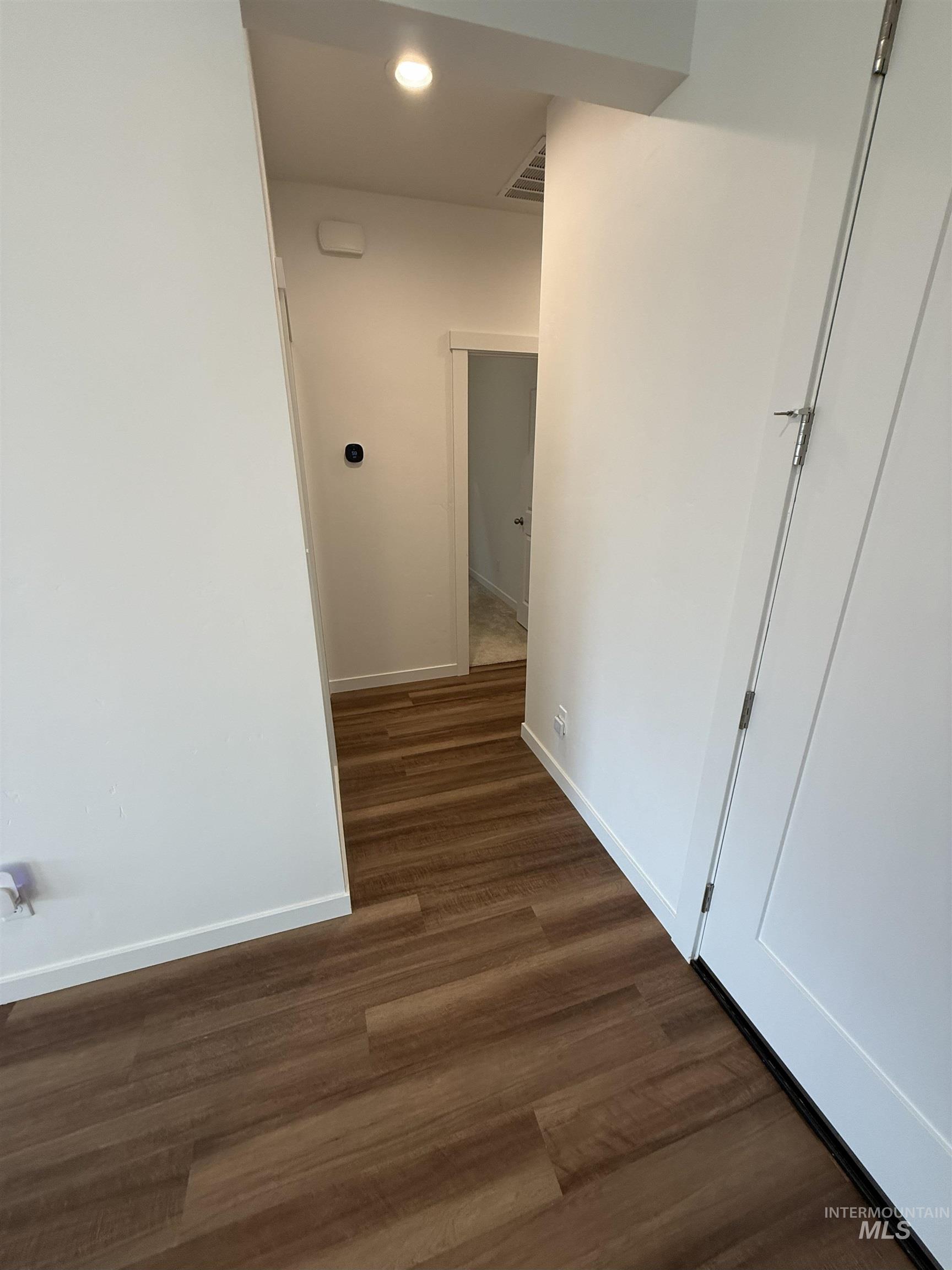 Hall with dark wood-style flooring and recessed lighting