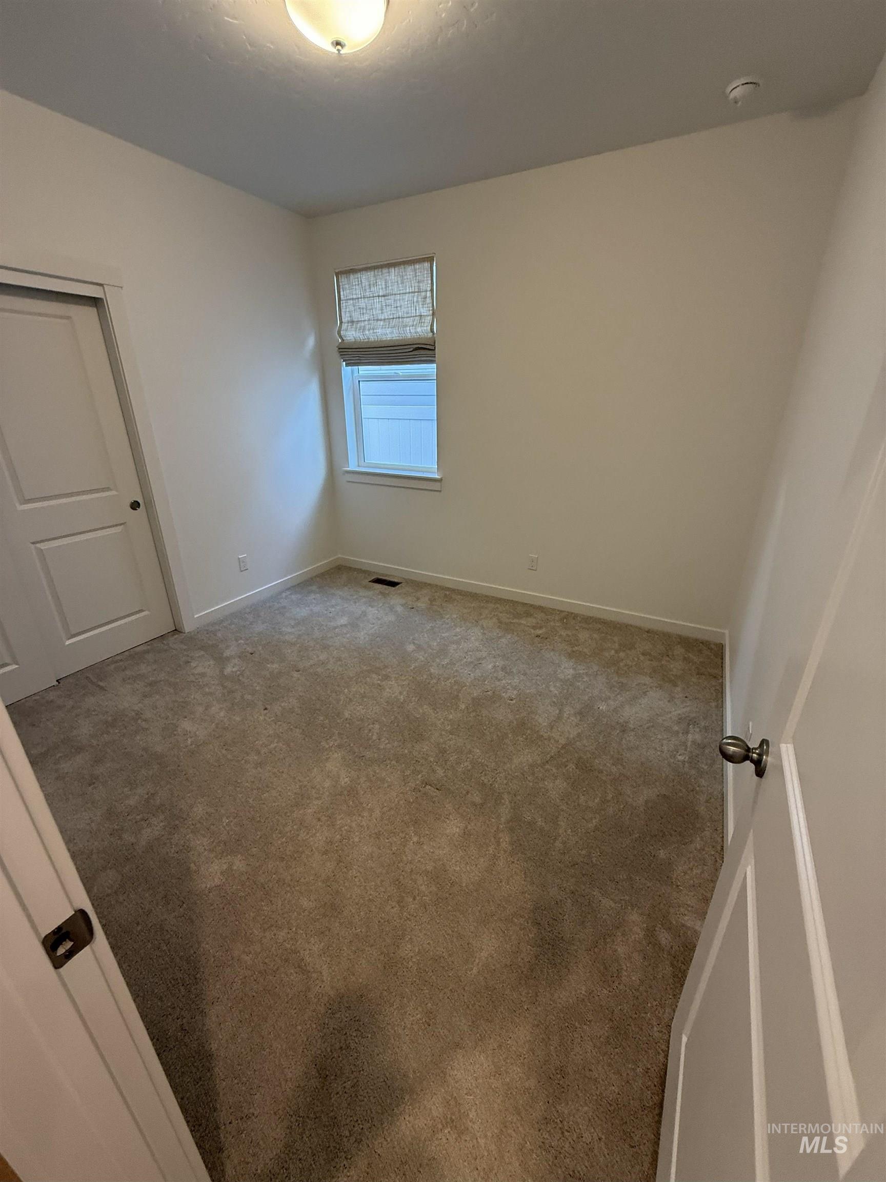 Unfurnished bedroom featuring carpet, closet and custom window coverings