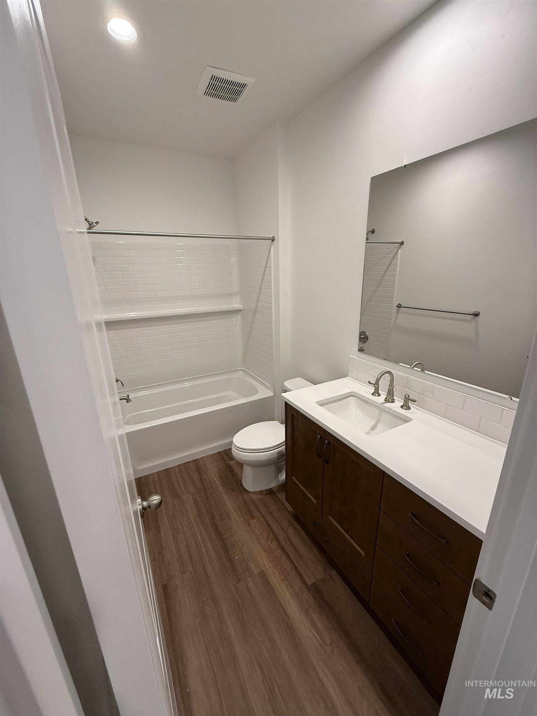 Full bath with shower / washtub combination, vanity, dark wood finished floors, and recessed lighting
