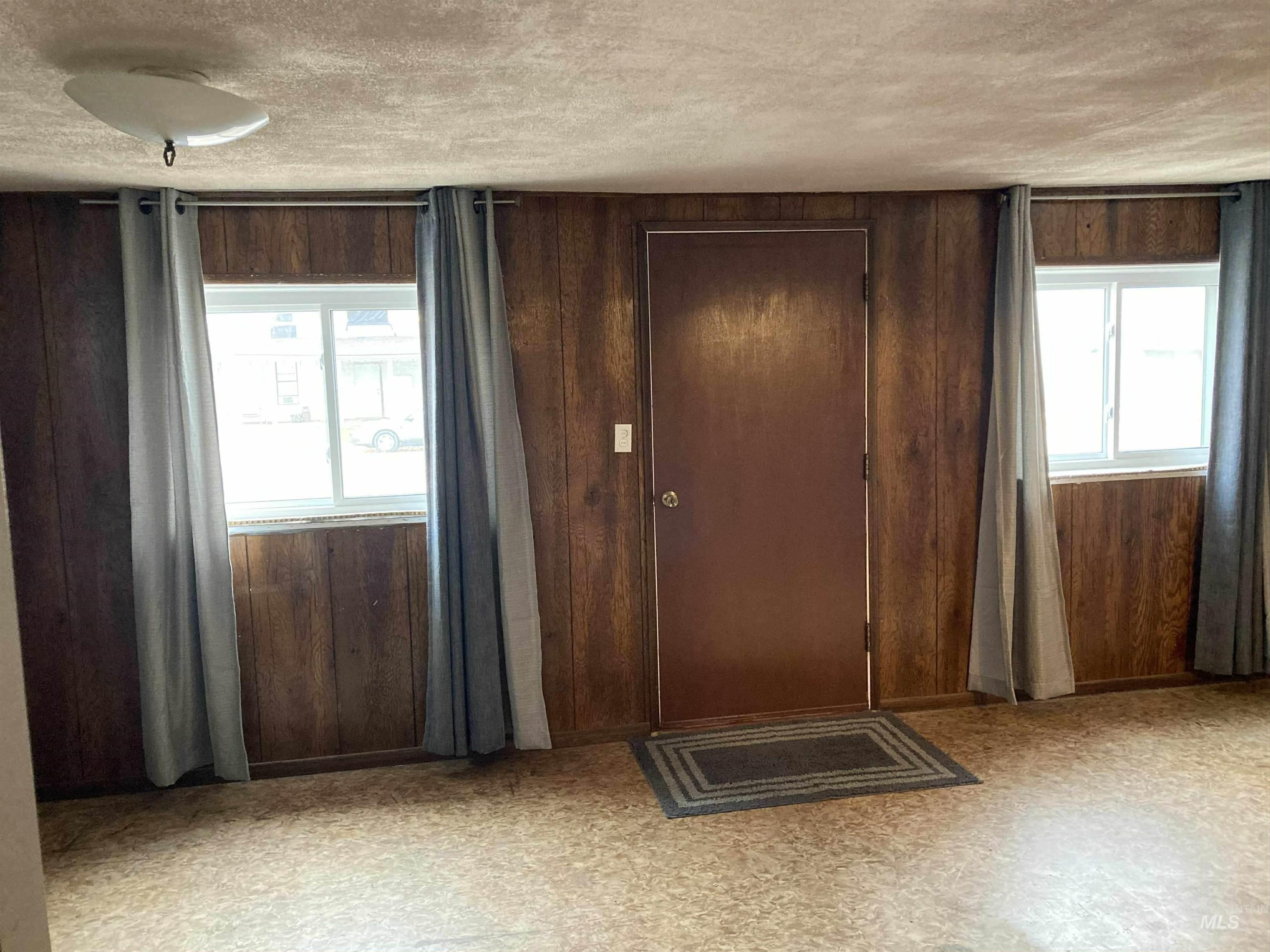Unfurnished bedroom with light floors, wood walls, and a textured ceiling