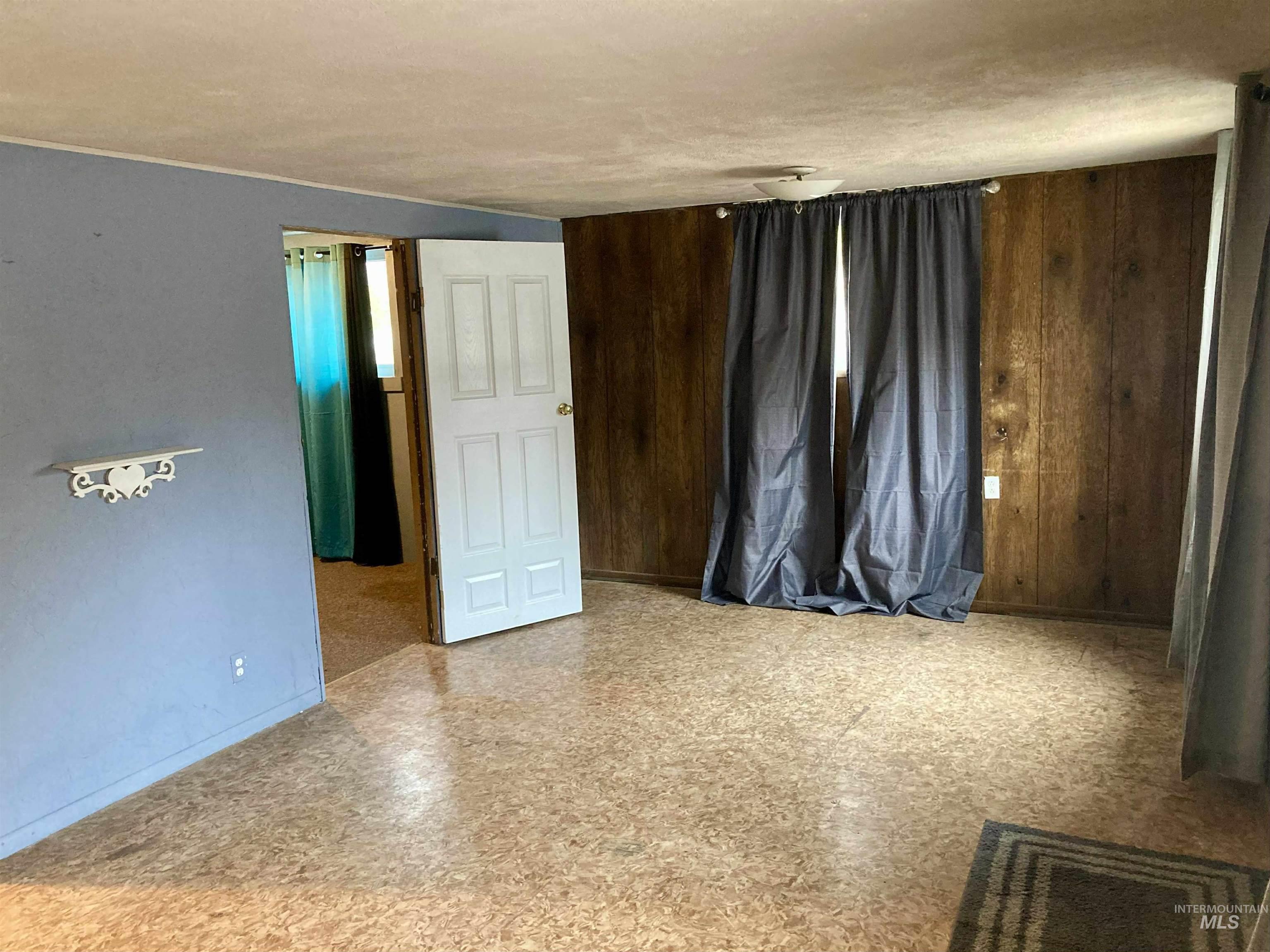 Unfurnished bedroom with wood walls and light floors