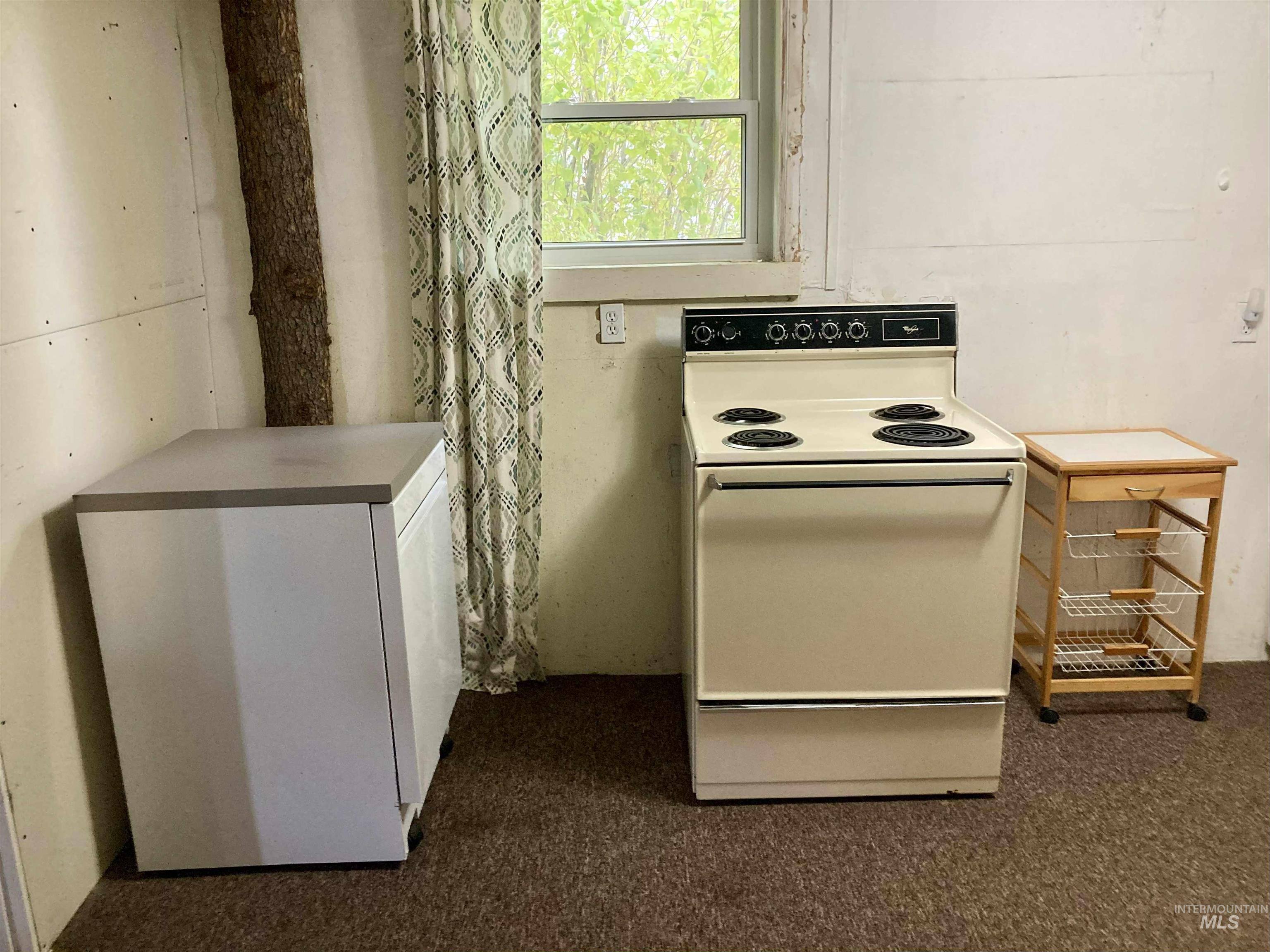 Kitchen featuring white electric range oven, white cabinetry, and dark colored carpet