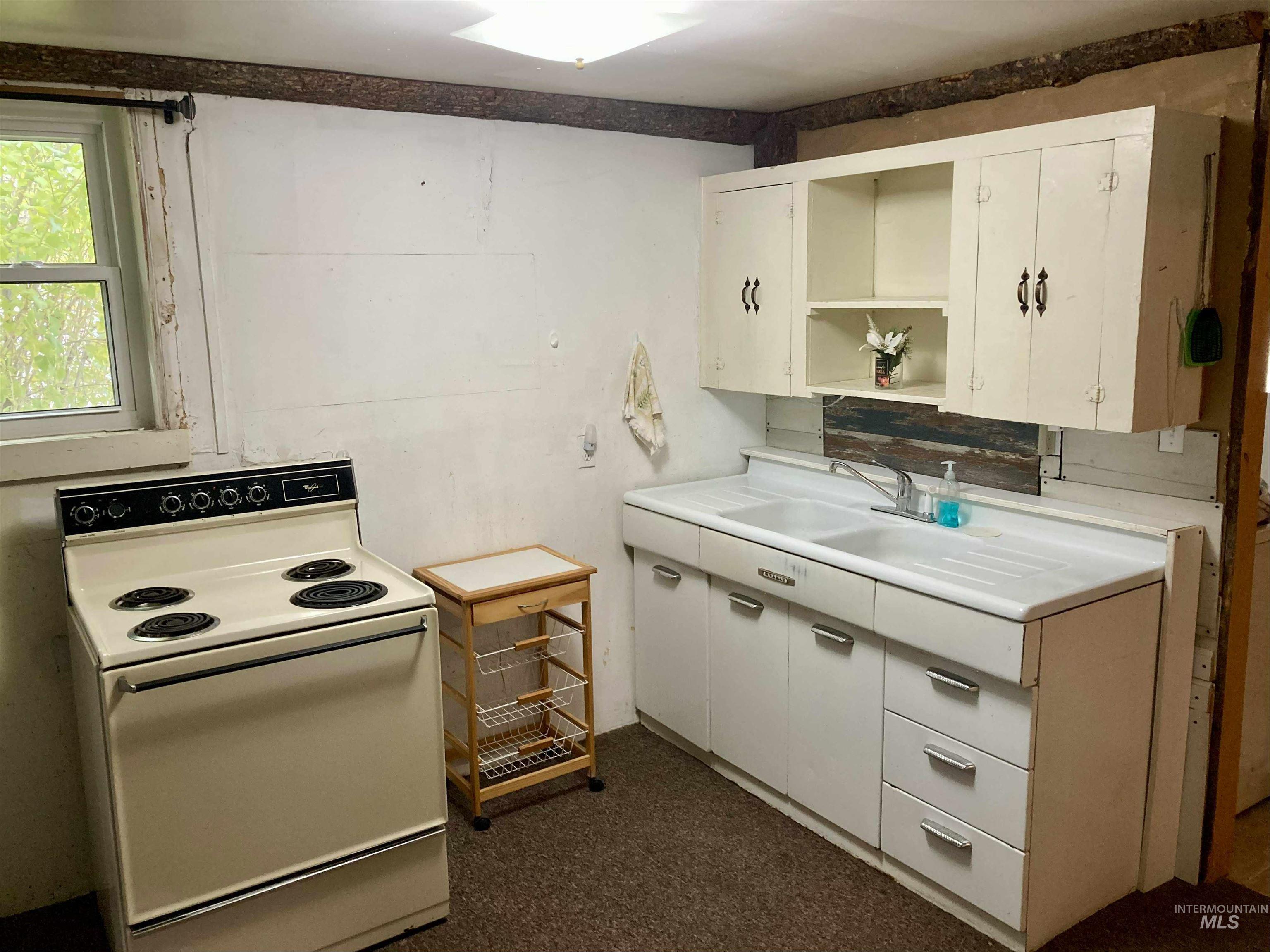 Kitchen with open shelves, white electric stove, light countertops, and white cabinets