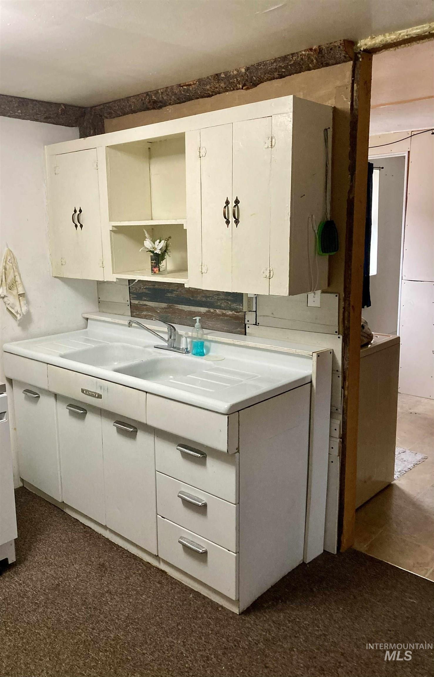 Kitchen with open shelves, light countertops, and white cabinets