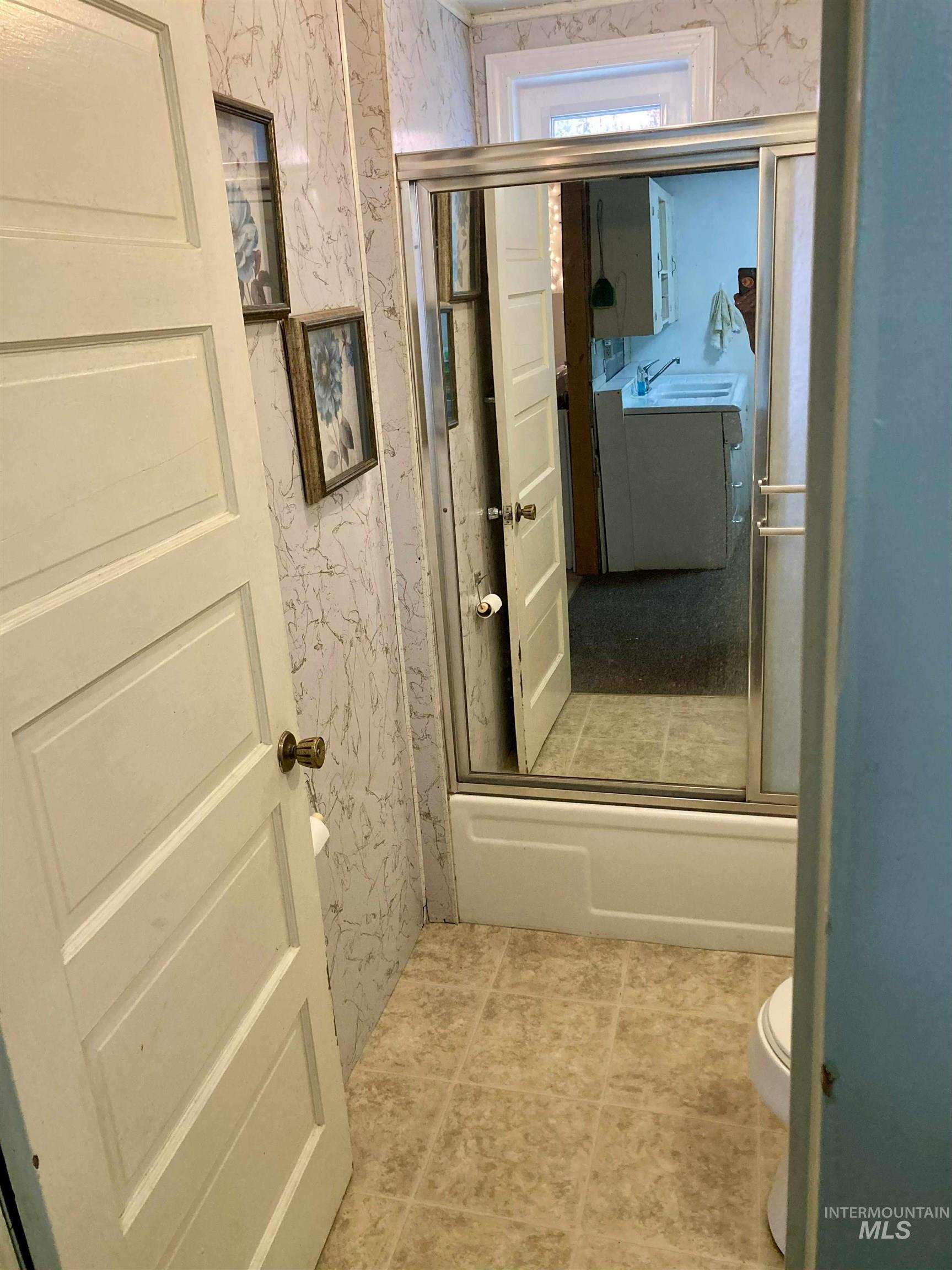 Bathroom featuring wallpapered walls and light tile patterned flooring