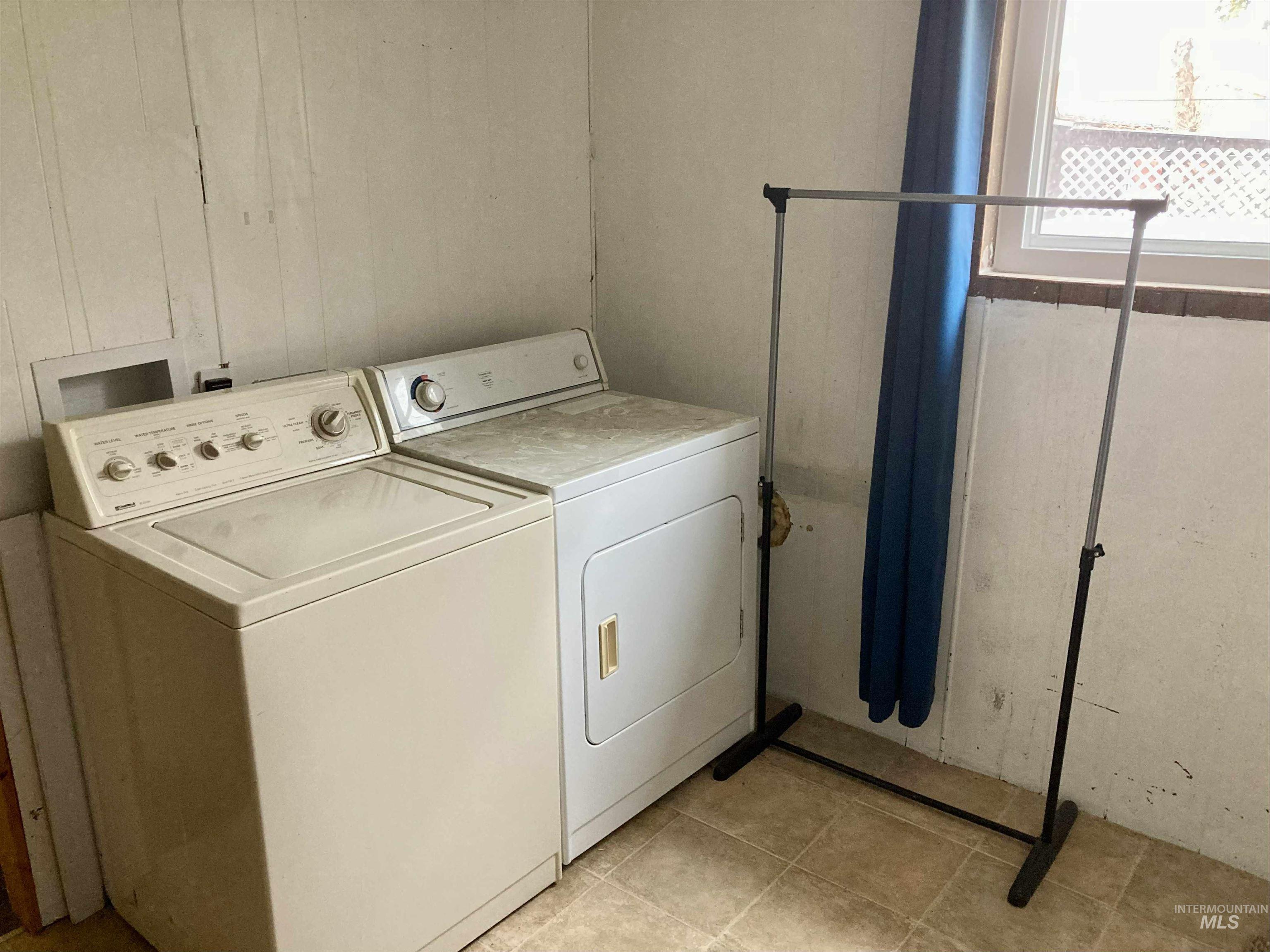 Washroom featuring light tile patterned flooring and washing machine and dryer