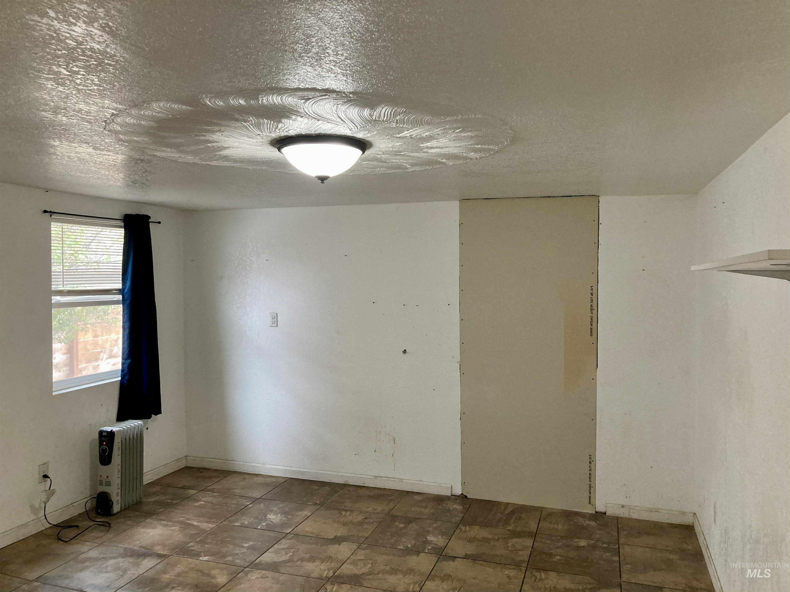 Empty room featuring a textured ceiling and baseboards