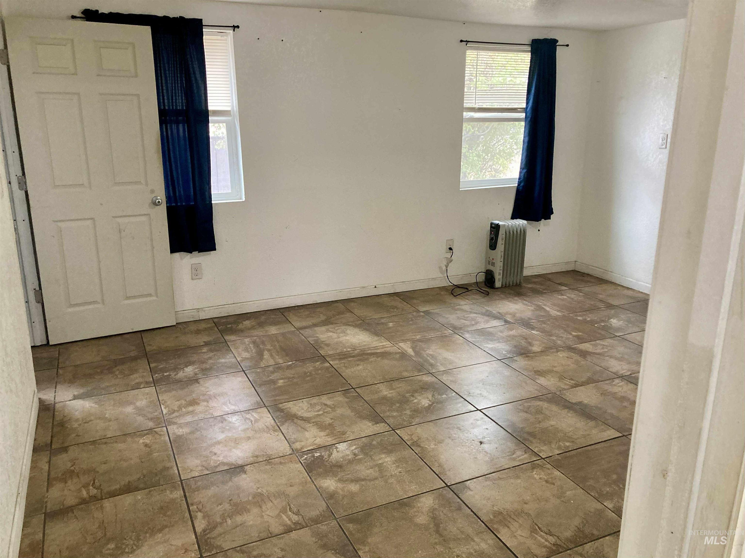 Tiled spare room with radiator heating unit and baseboards
