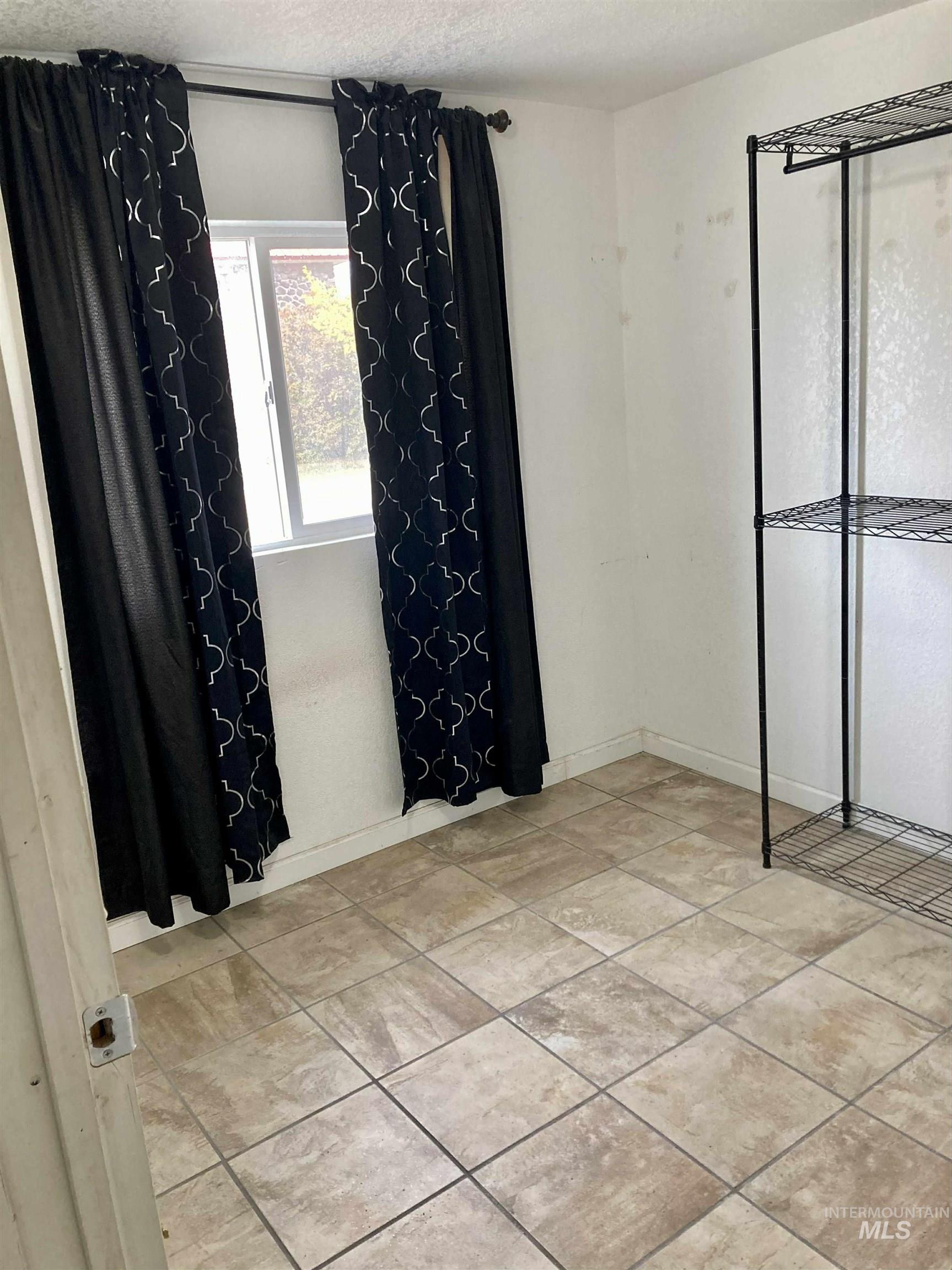 Unfurnished bedroom featuring a textured ceiling and light tile patterned floors