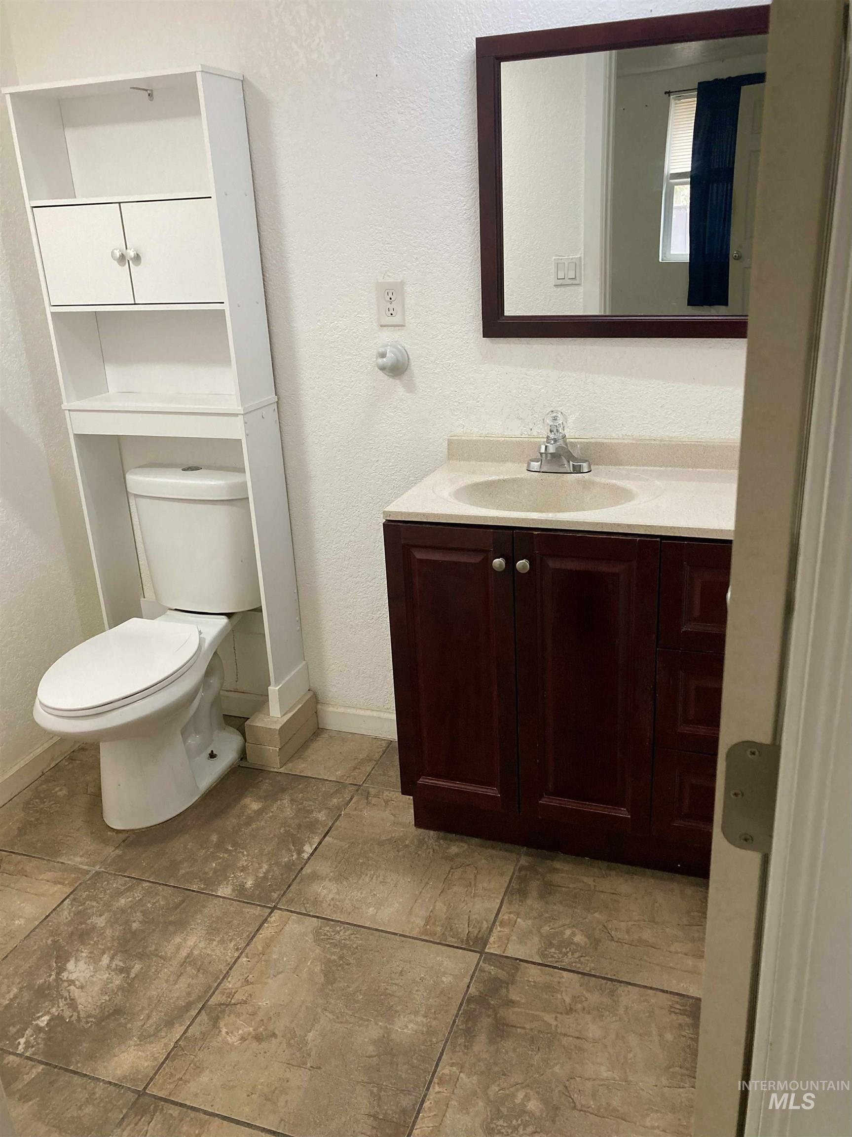 Bathroom featuring vanity, a textured wall, and light tile patterned floors