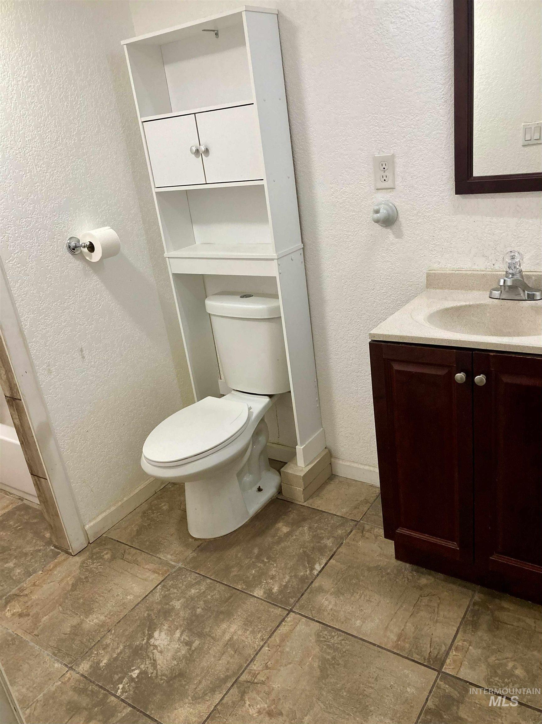 Bathroom featuring a textured wall and vanity