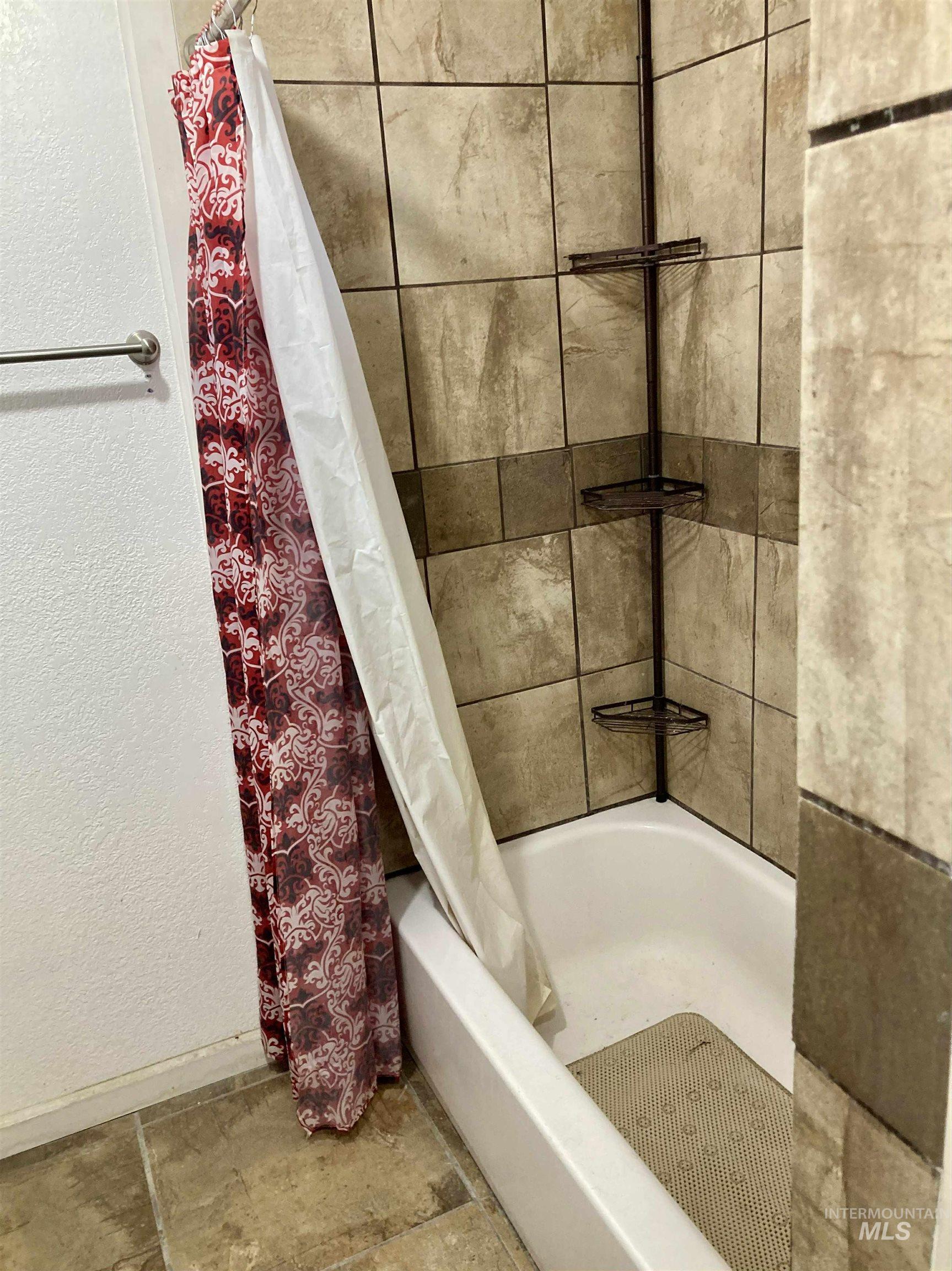 Bathroom featuring shower / bath combination with curtain and a textured wall
