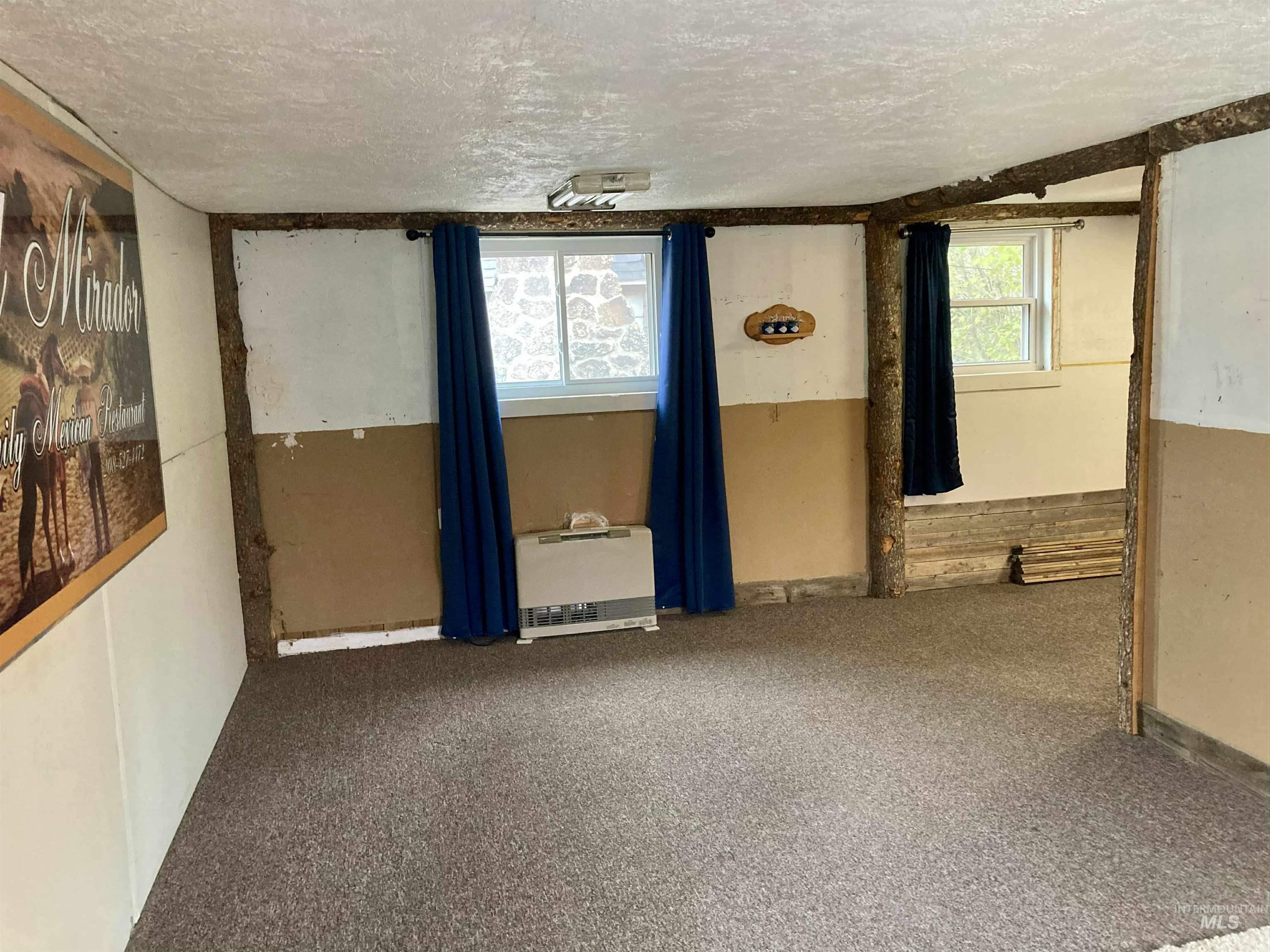 Carpeted spare room with a textured ceiling and heating unit