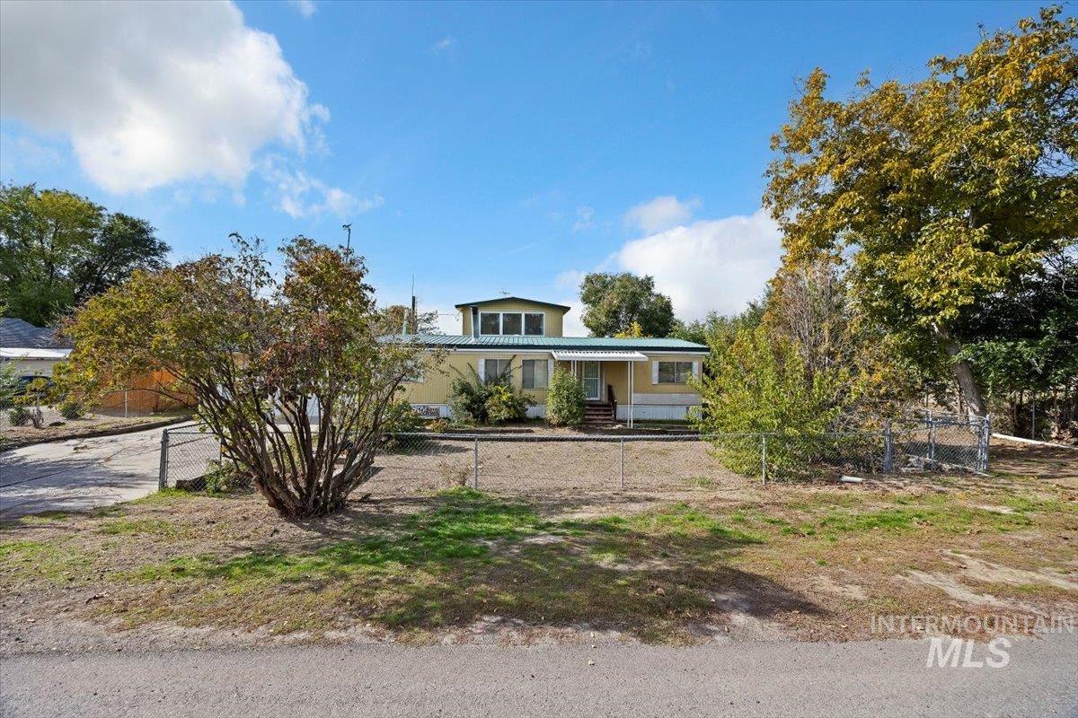 View of front of home featuring a porch, a fenced front yard, and a metal roof