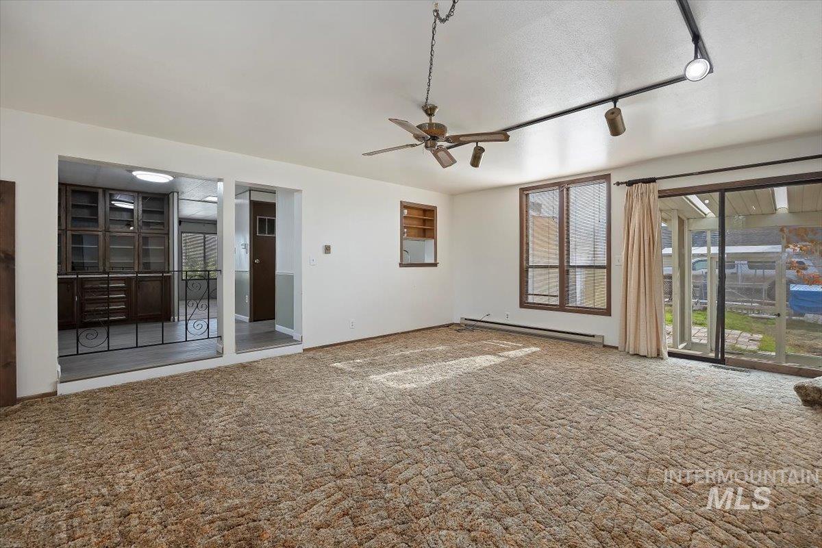Spare room featuring carpet, baseboard heating, track lighting, a ceiling fan, and a textured ceiling