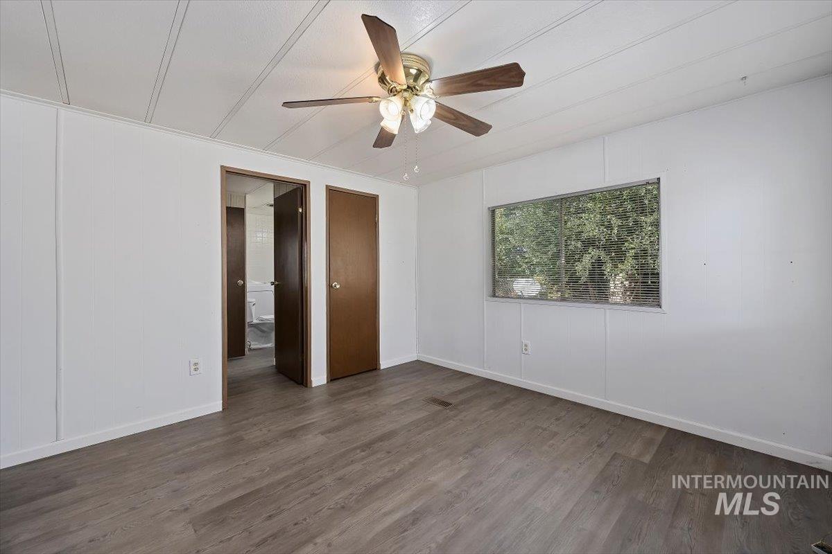 Empty room with dark wood-style flooring and ceiling fan