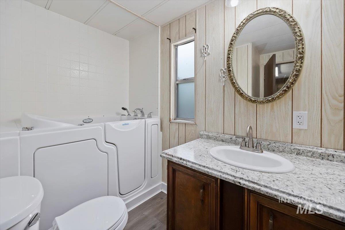 Bathroom featuring a bath, vanity, and dark wood-type flooring