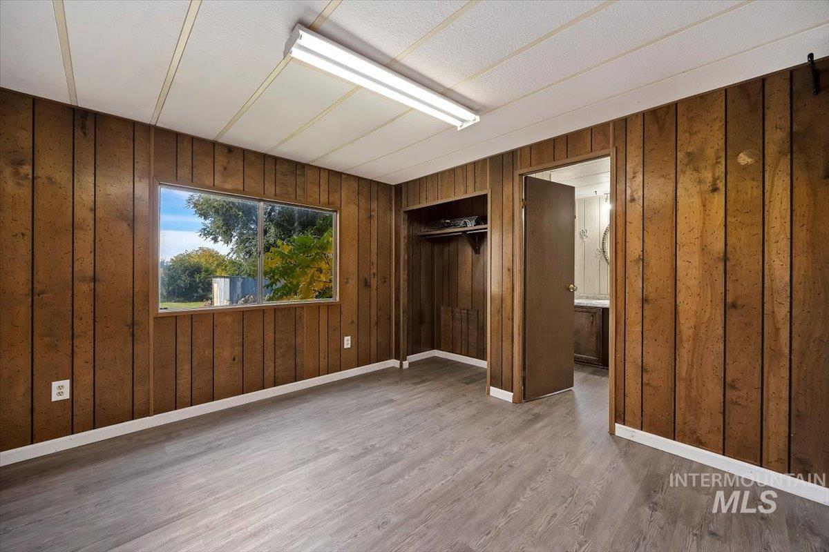 Unfurnished bedroom with wood walls, wood finished floors, and a closet