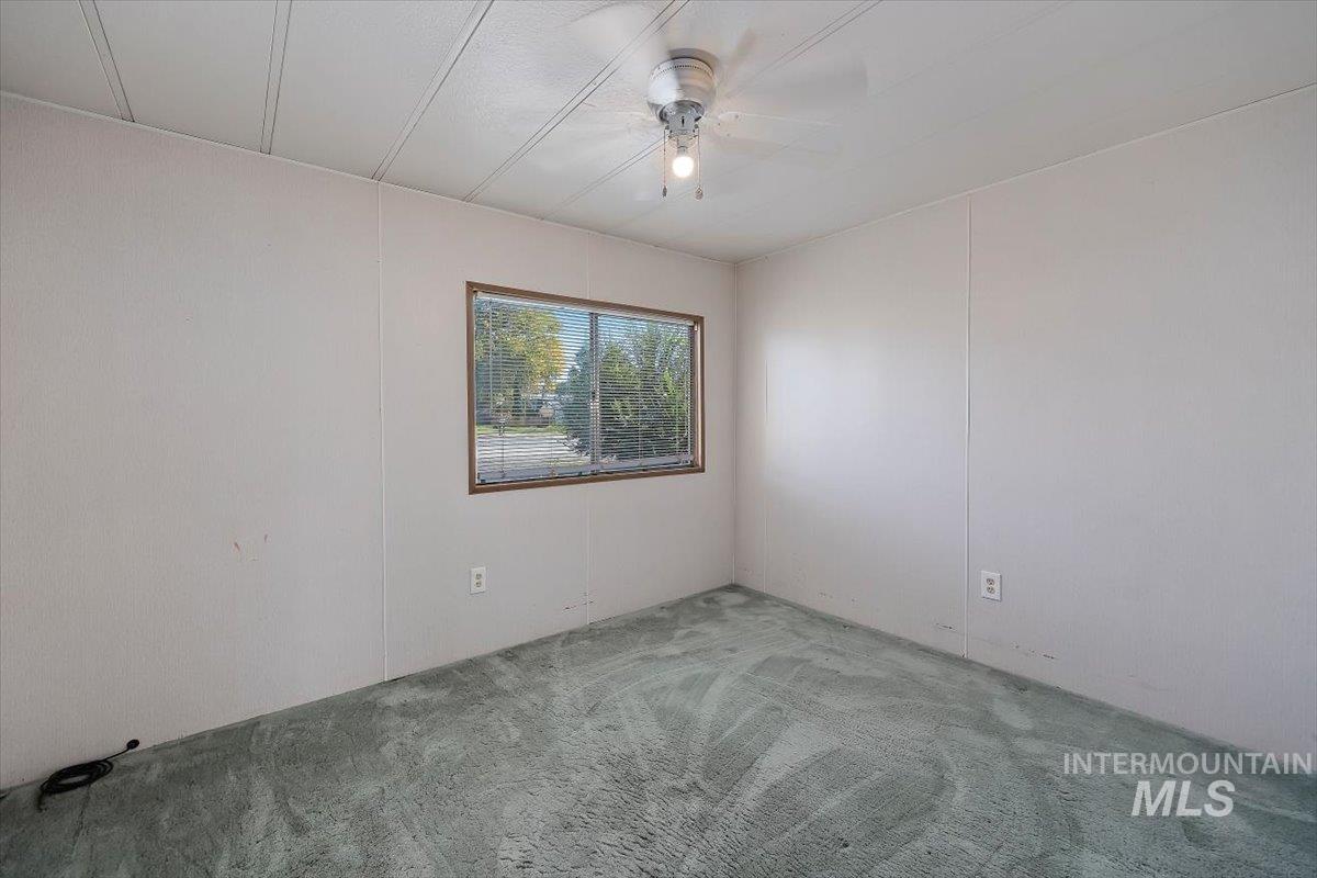 Carpeted spare room featuring a ceiling fan