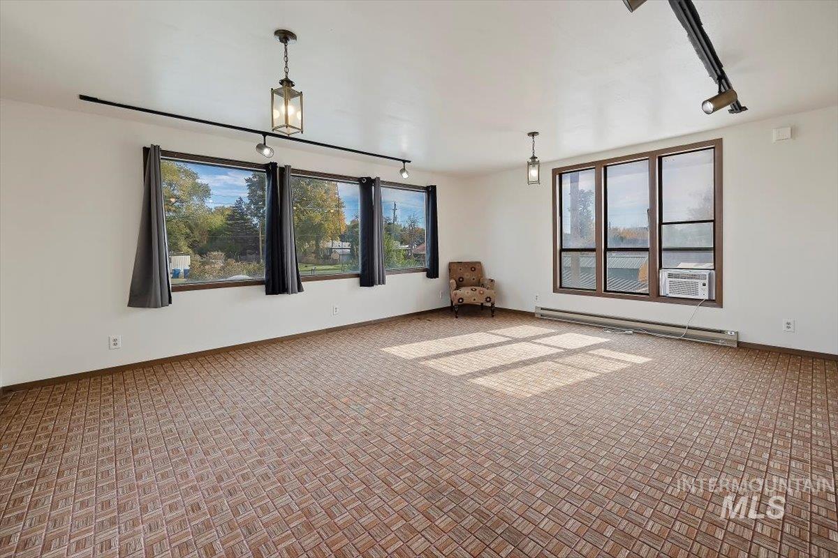Carpeted empty room featuring track lighting and a baseboard heating unit