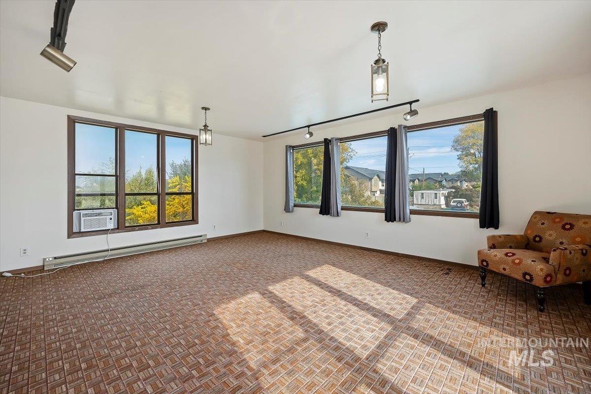 Unfurnished room featuring rail lighting and a baseboard heating unit
