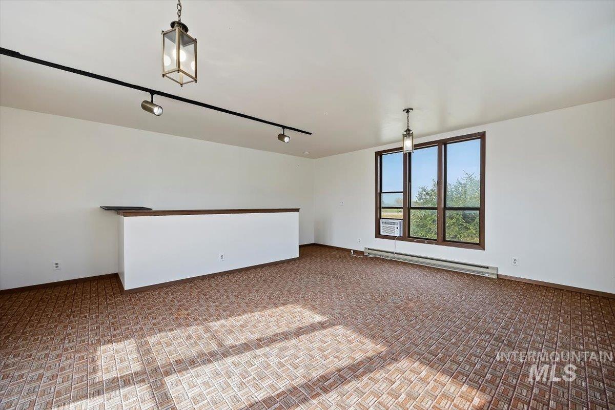 Empty room with a baseboard radiator, track lighting, and carpet floors